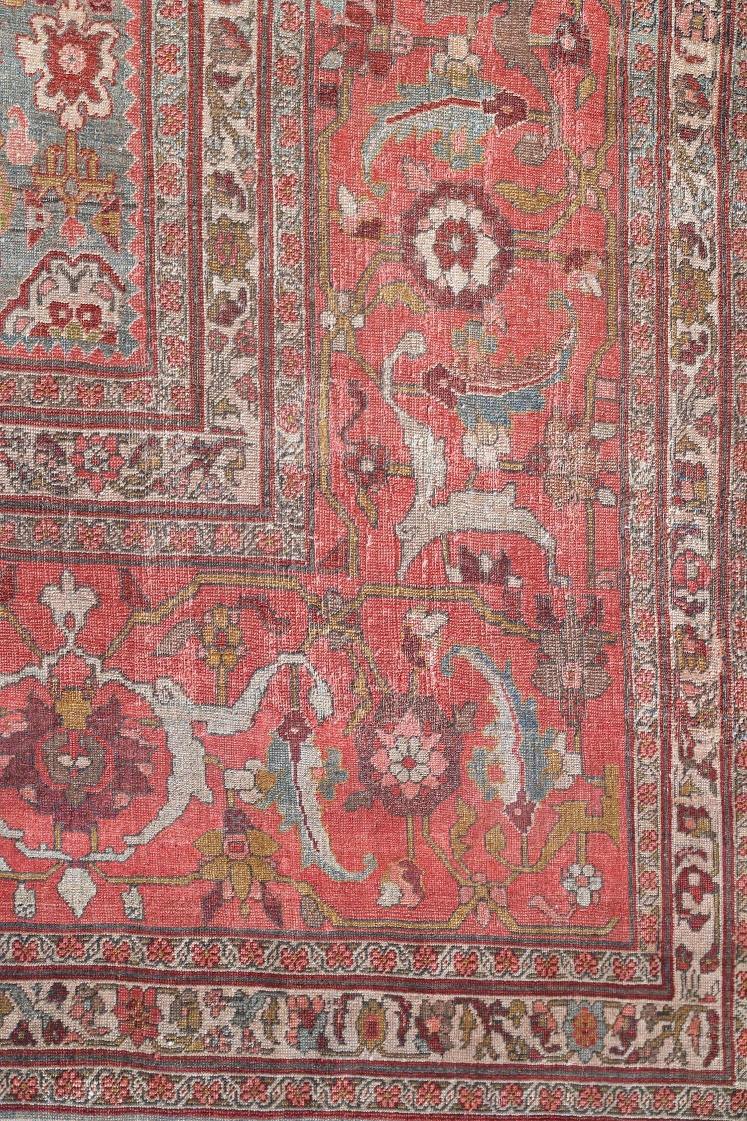 Handwoven Bijar rug detail:  reddish-pink field with intricate floral and animal motifs, muted tones.
