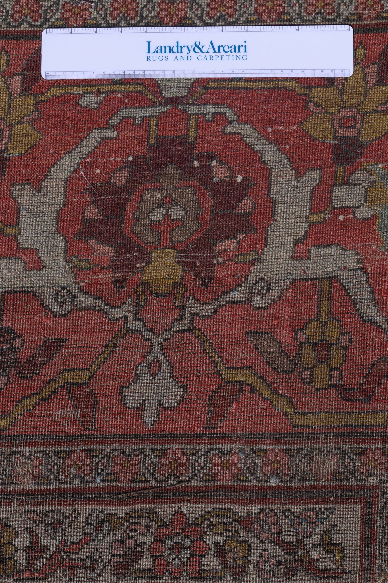 Close-up detail of an antique Bijar rug's handwoven floral pattern, showcasing its reddish-brown tones and intricate design.
