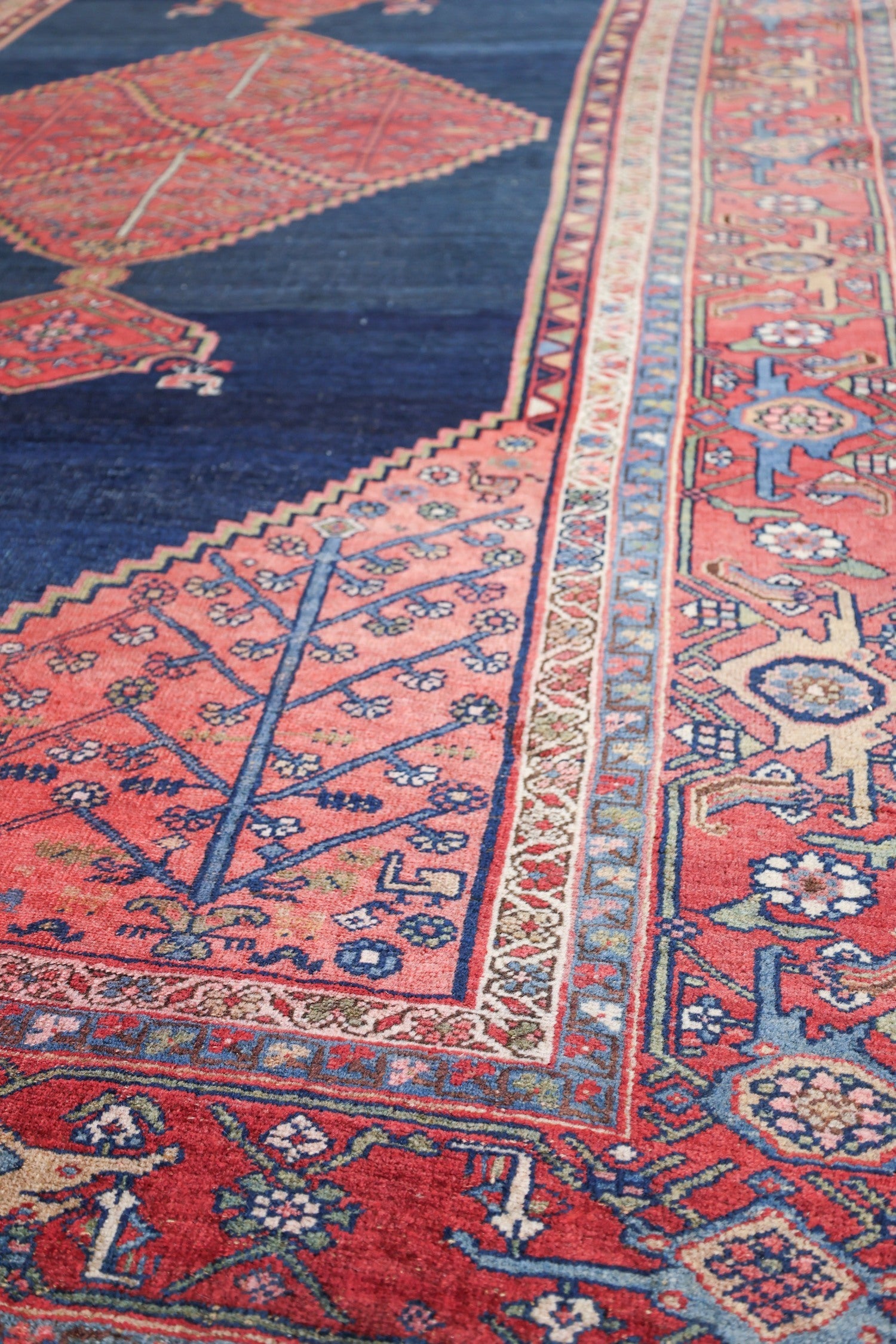 Handwoven tribal rug detail: red and blue floral pattern, antique Bijar design.
