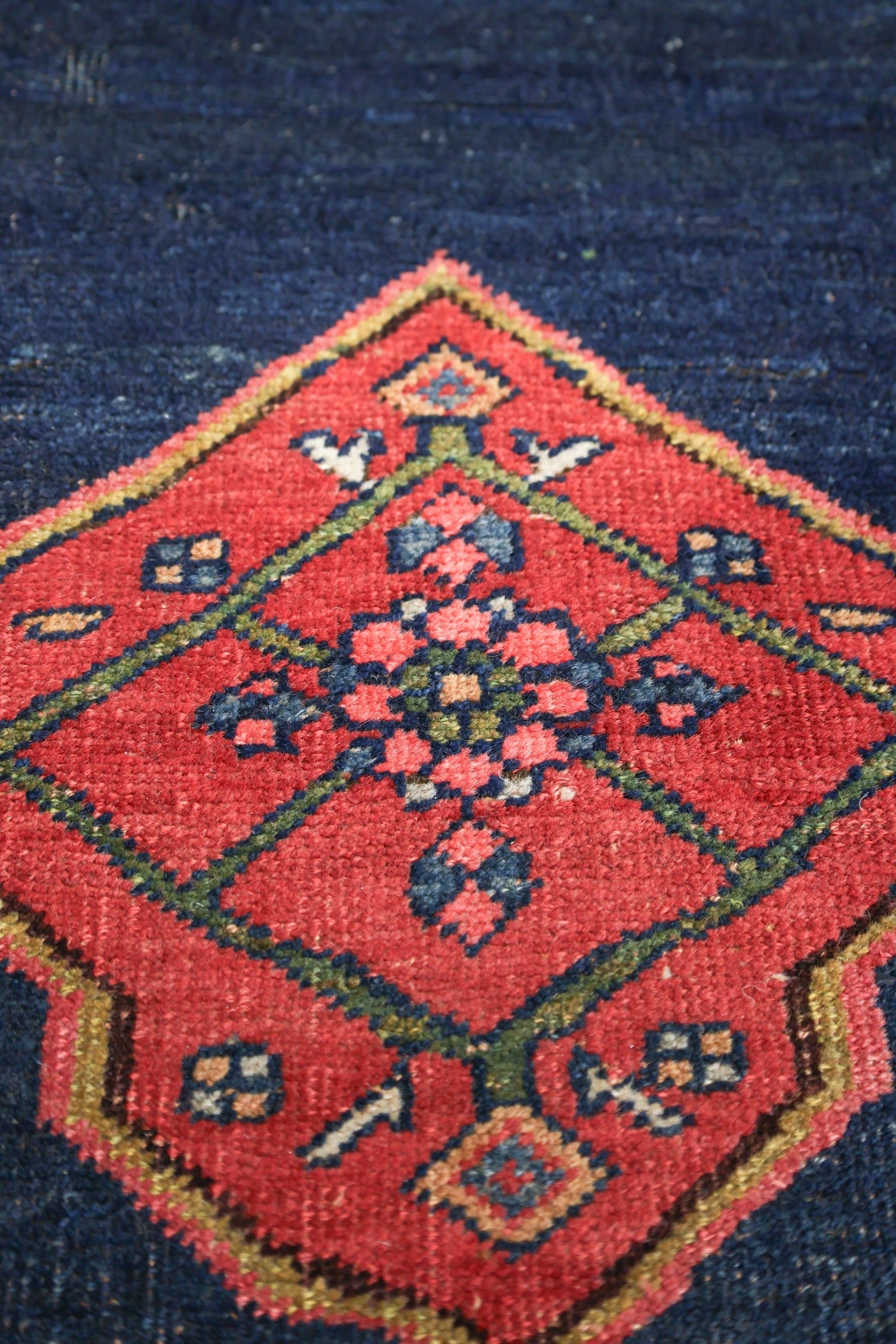 Close-up of a handwoven rug detail, showcasing a vibrant red and navy pattern.
