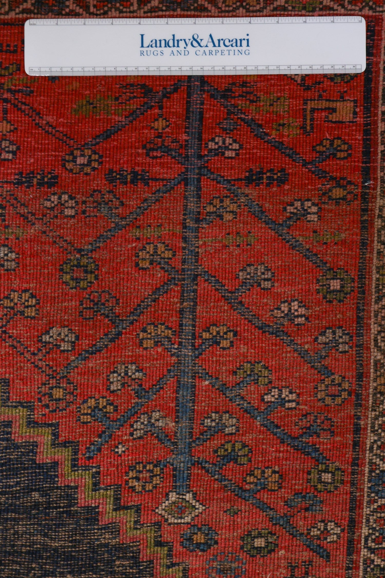 Close-up detail of a red and blue antique tribal rug, showcasing intricate handwoven patterns.
