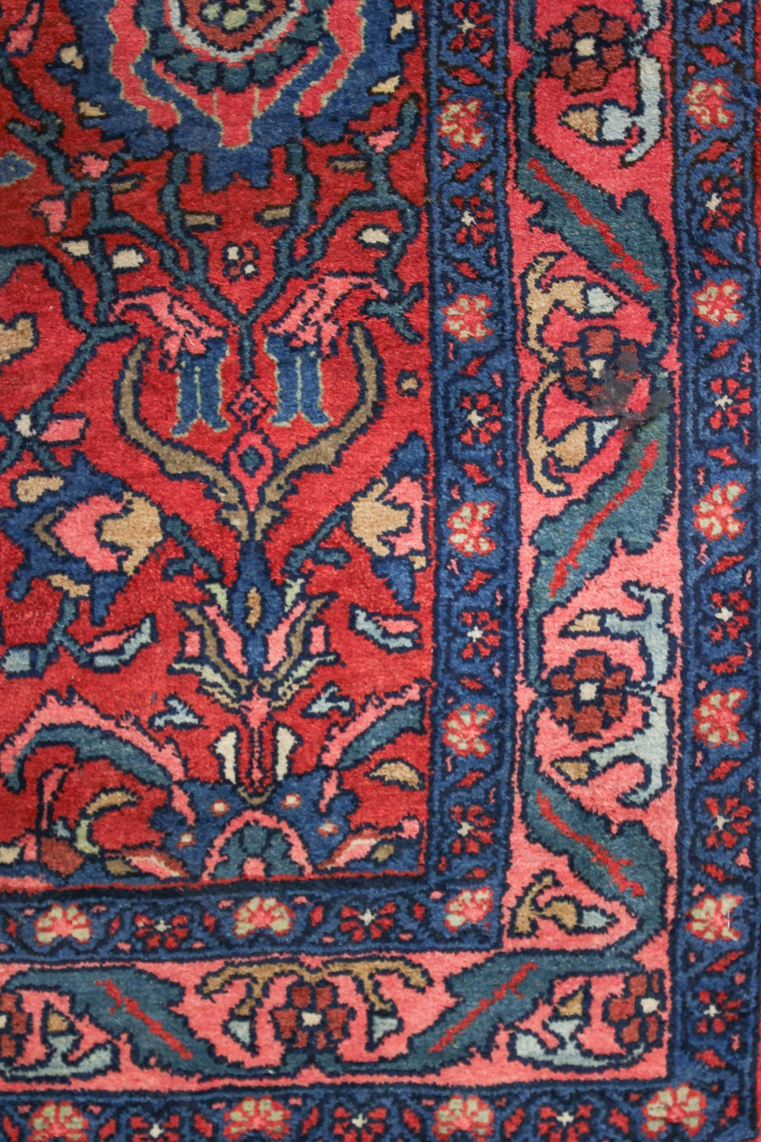 Intricate detail of a red and blue handwoven rug, showcasing traditional floral patterns.
