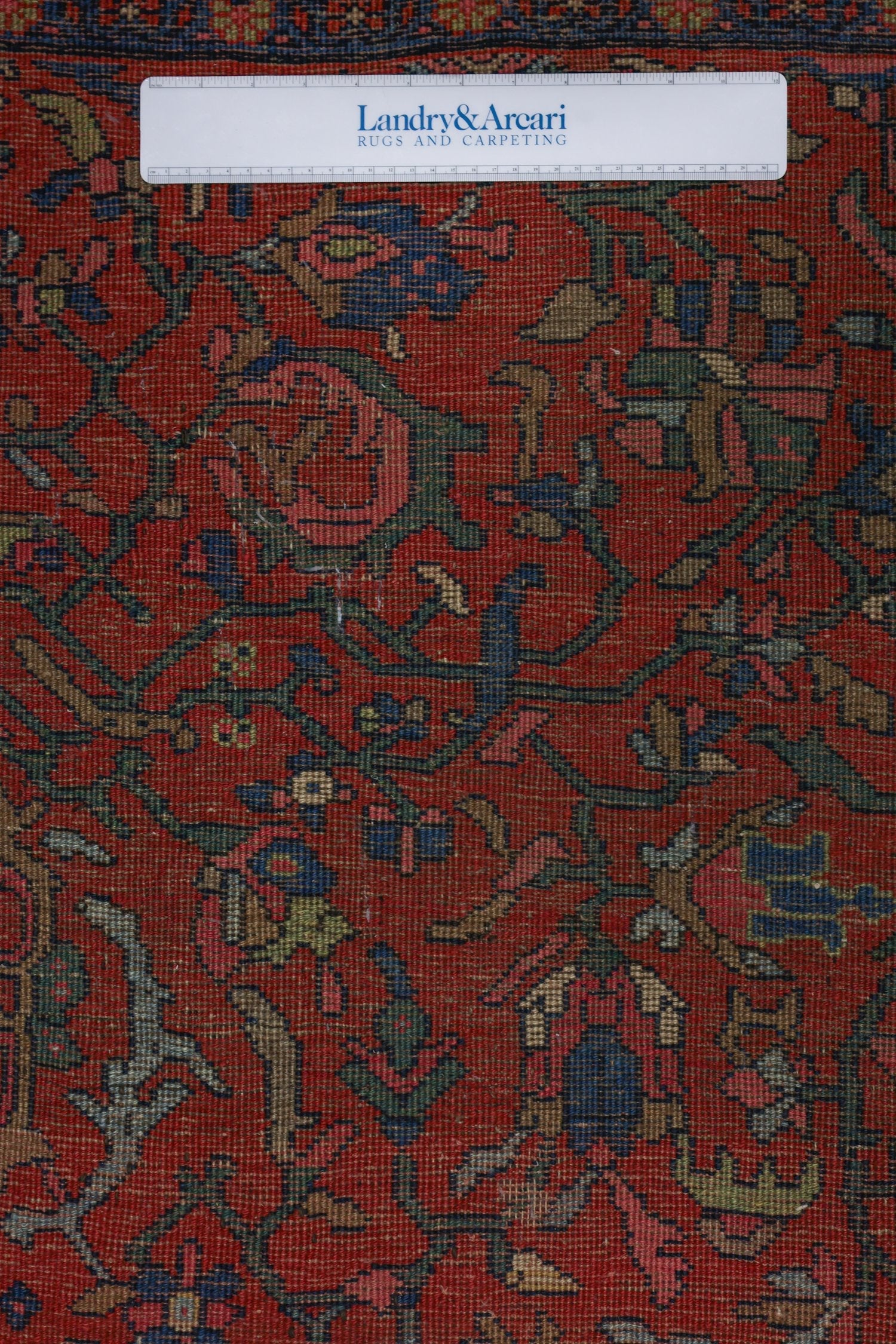 Close-up detail of antique Bijar rug's intricate, handwoven pattern in red, blue, and green hues.
