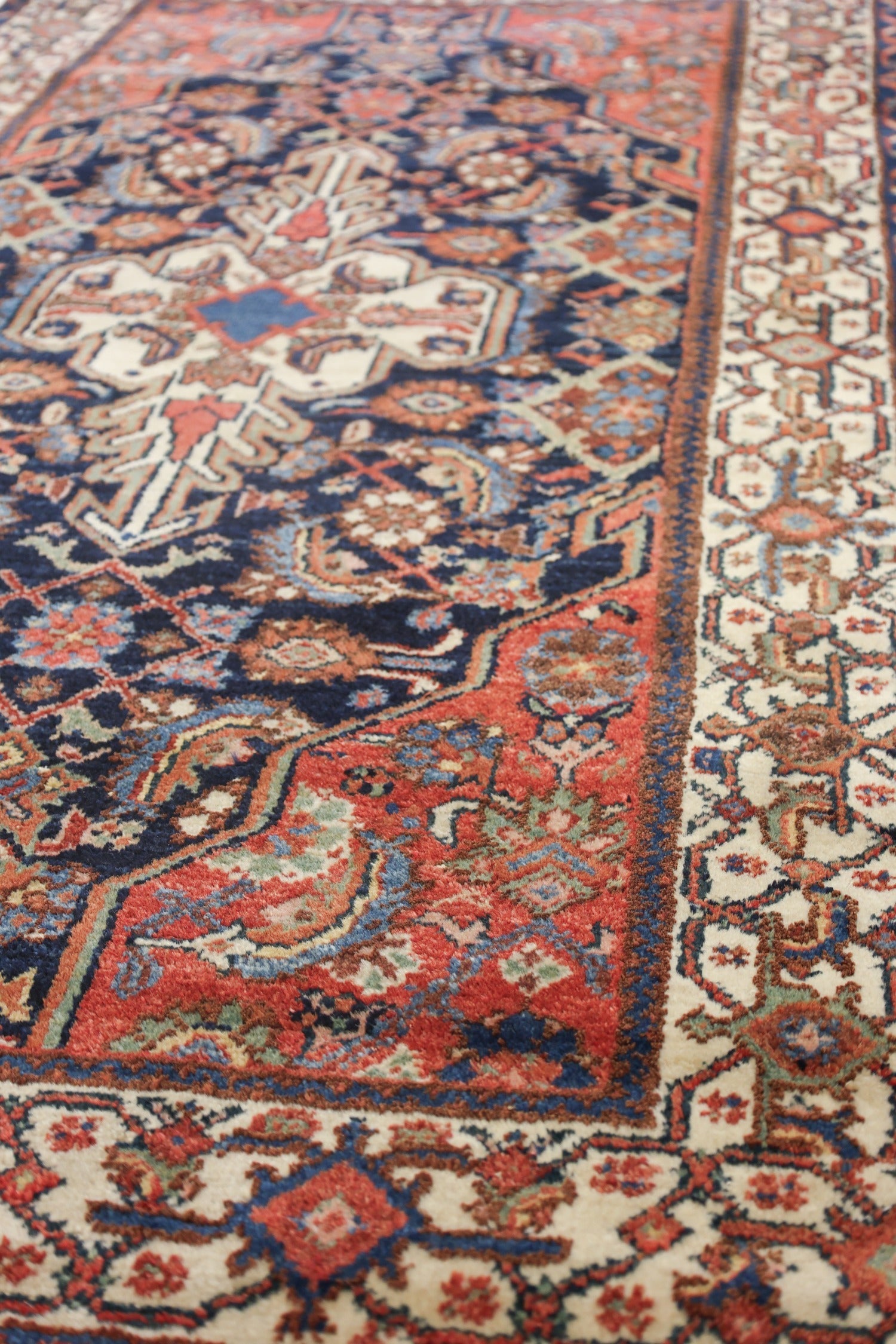 Detail of an antique handwoven rug with intricate red, blue, and cream patterns.
