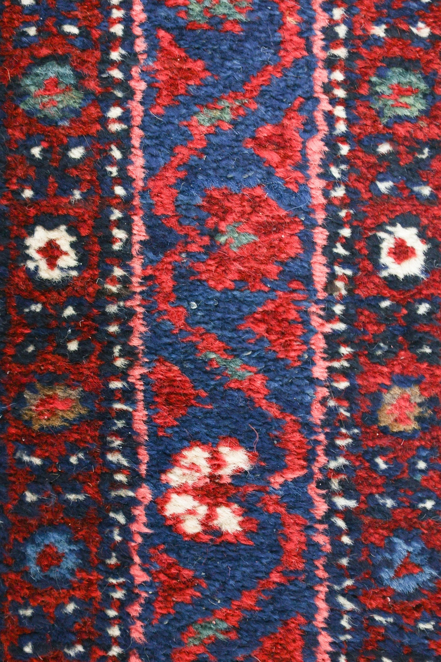 Close-up detail of a handwoven rug's rich red and blue pattern.
