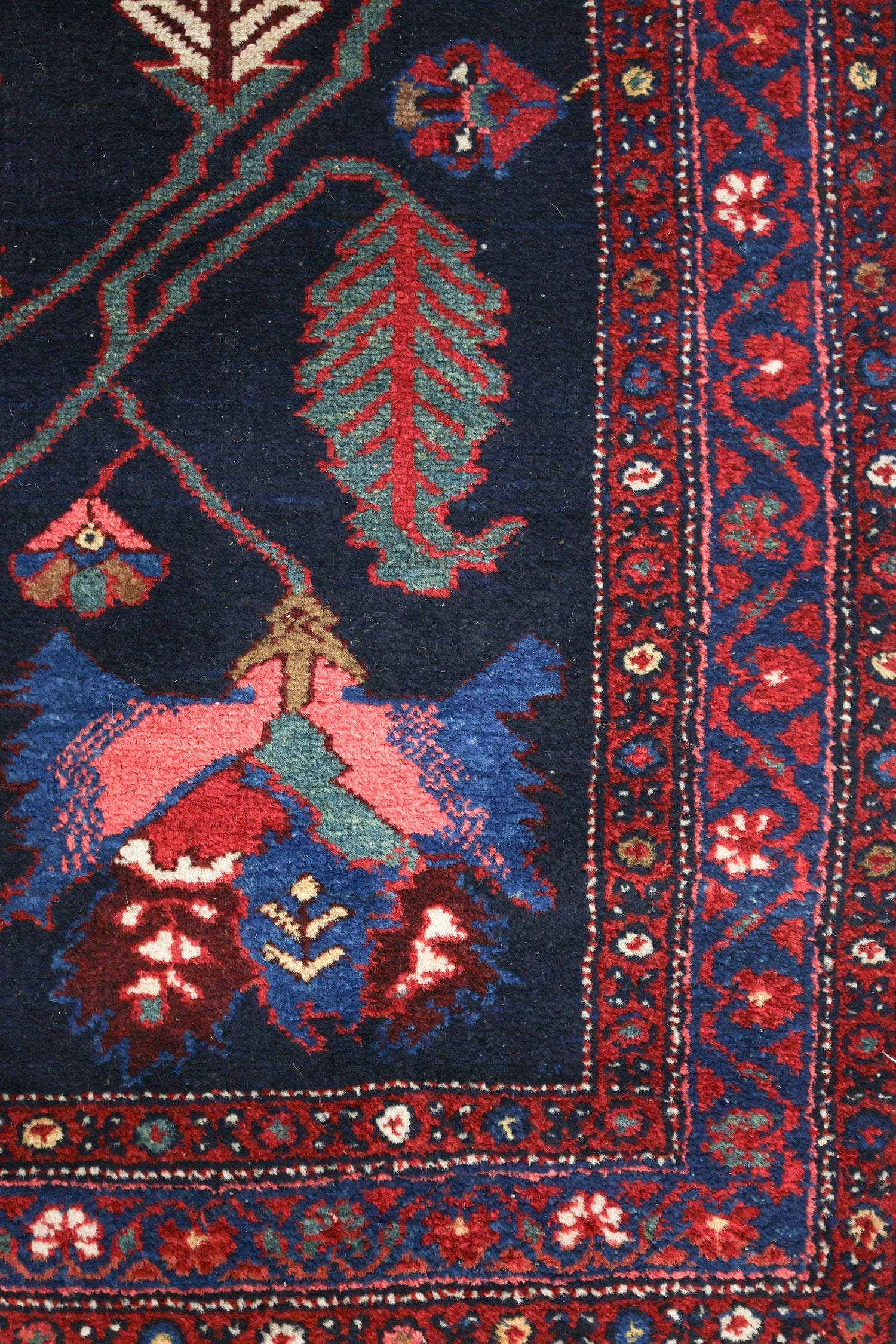 Detail of antique Bakhtiari rug, showcasing navy blue field with red and teal floral patterns, and a richly patterned border.
