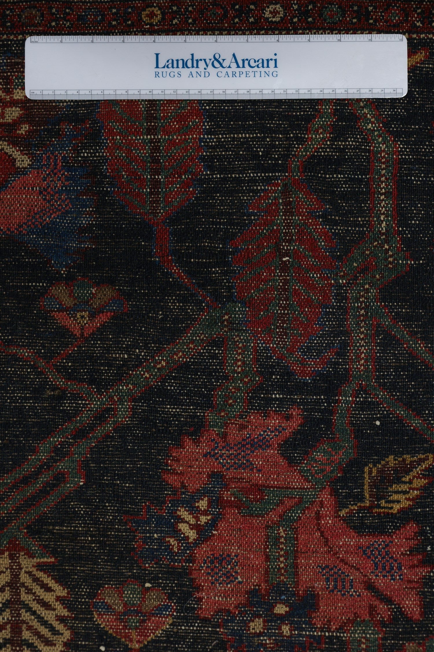 Close-up detail of antique Bakhtiari rug's intricate, dark-hued floral pattern.
