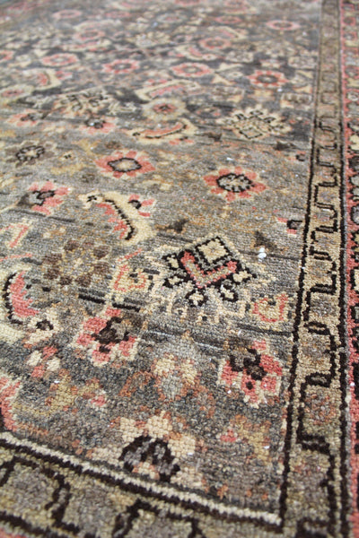 Close-up detail of an antique Hamadan rug, showcasing its intricate floral pattern in muted browns, creams, and pinks.
