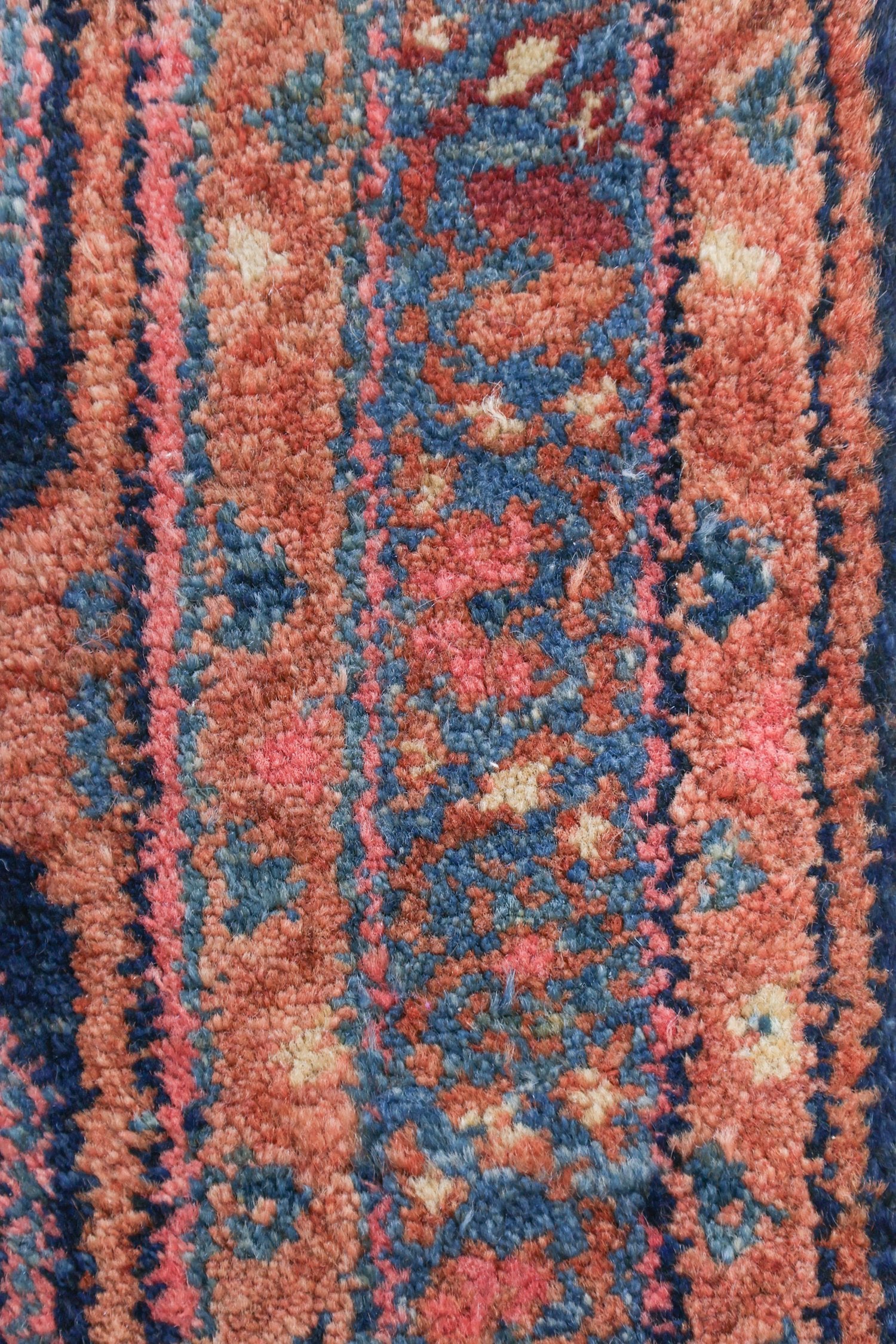 Close-up of handwoven rug detail, showcasing deep reds, blues, and creams in a tribal design.
