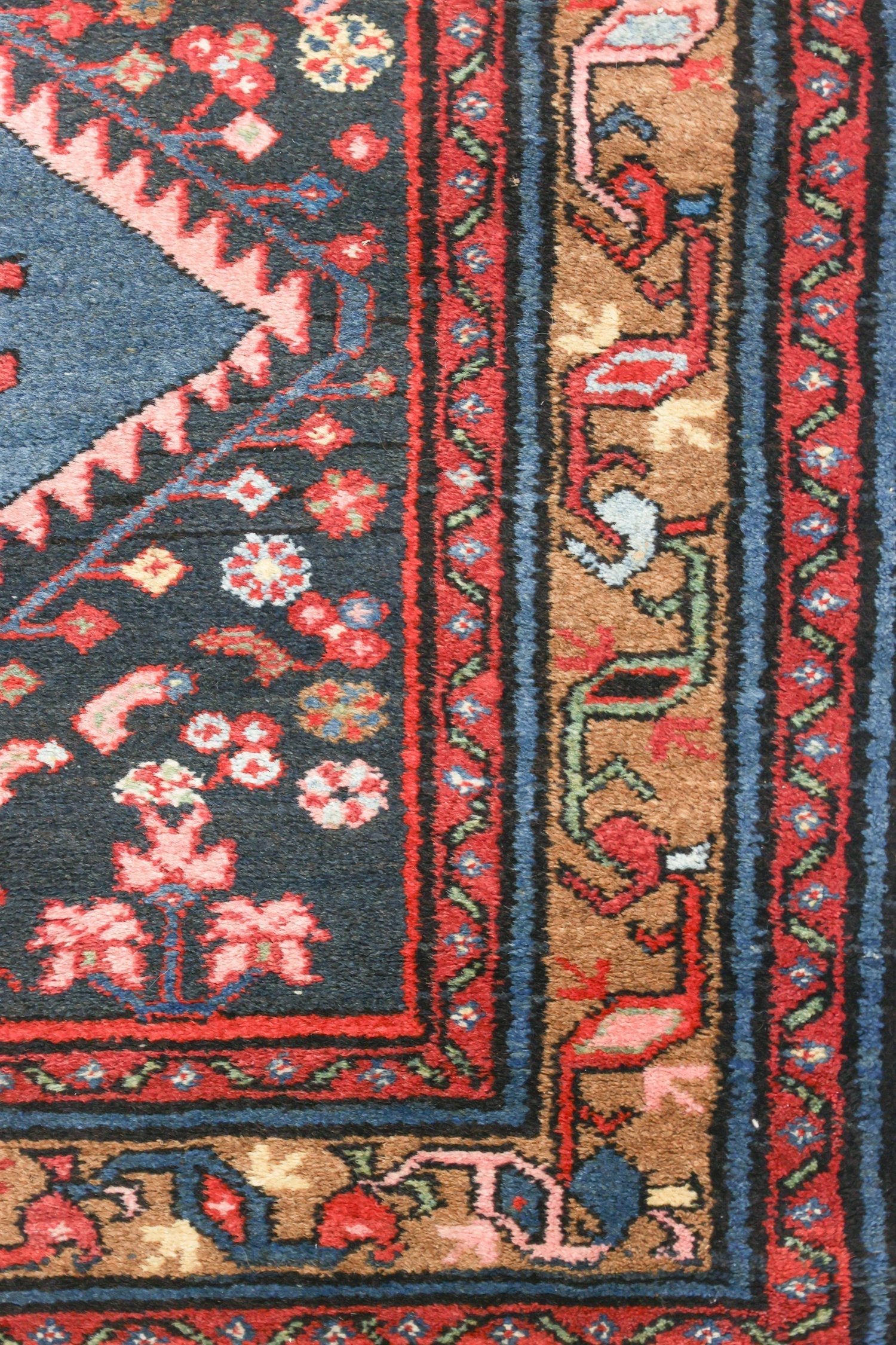 Handwoven rug detail: vibrant floral and geometric patterns in red, pink, blue, and brown.
