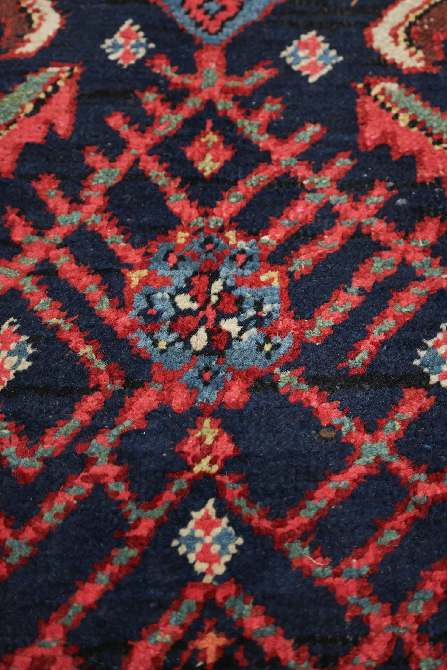 Close-up of a handwoven rug's intricate, red and blue tribal pattern.
