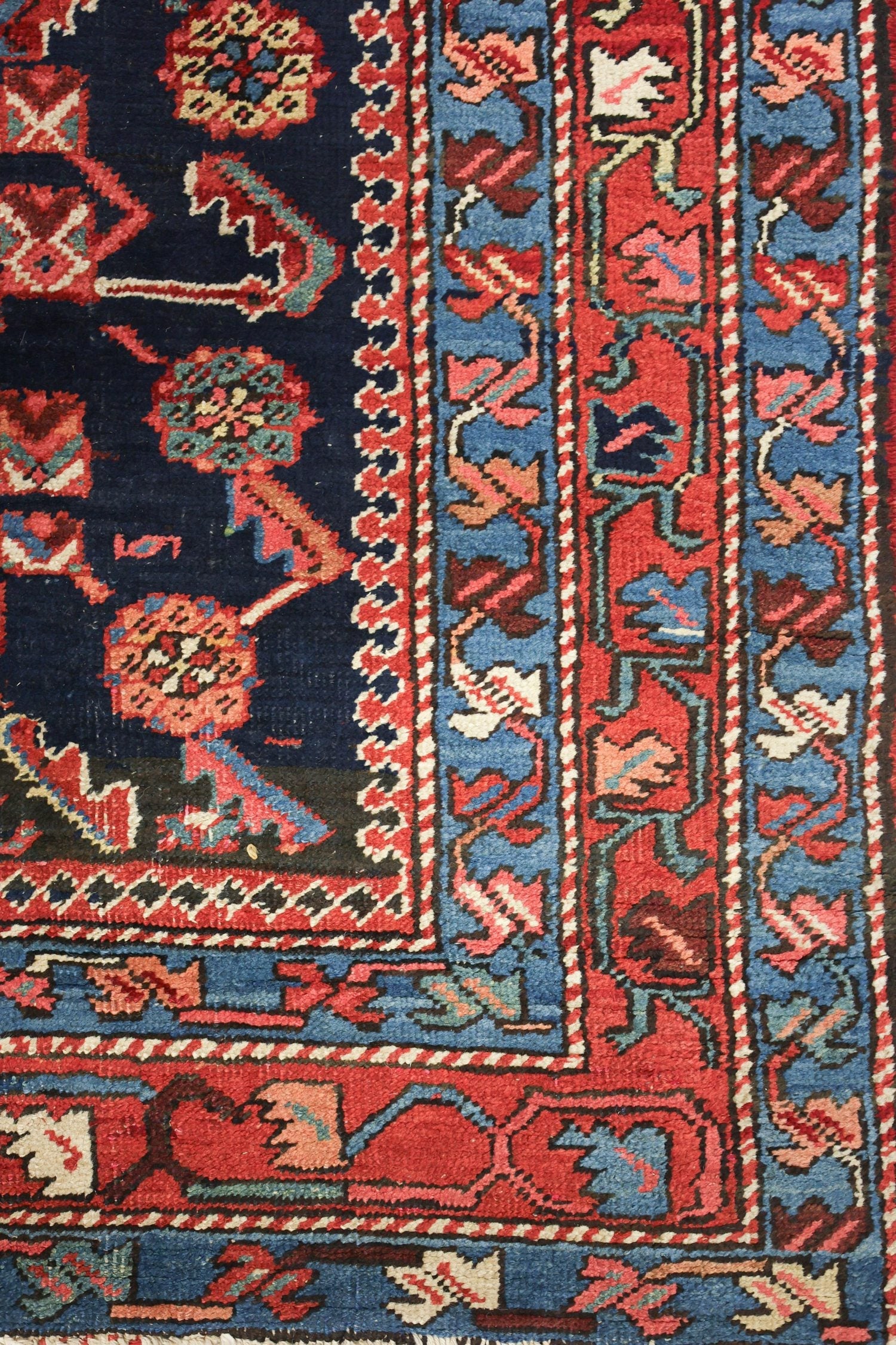 Handwoven Heriz rug detail, showcasing intricate blue, red, and ivory floral patterns.
