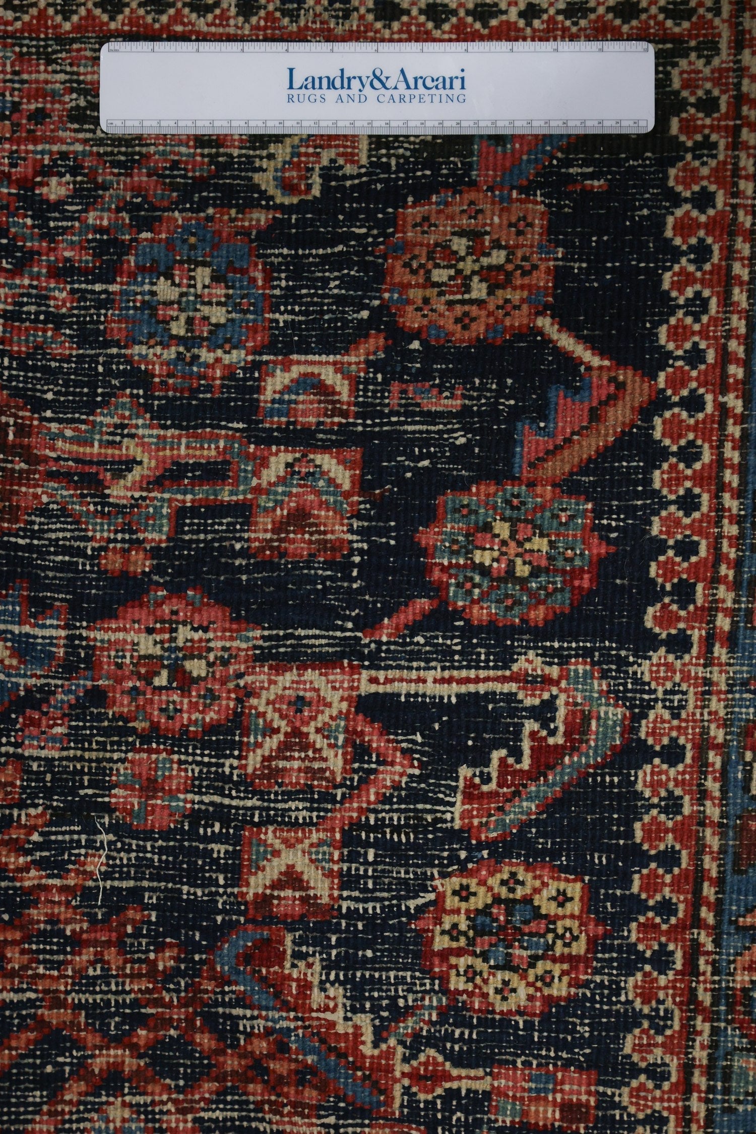 Close-up detail of an antique Heriz rug's intricate, handwoven pattern in deep blue and red hues.
