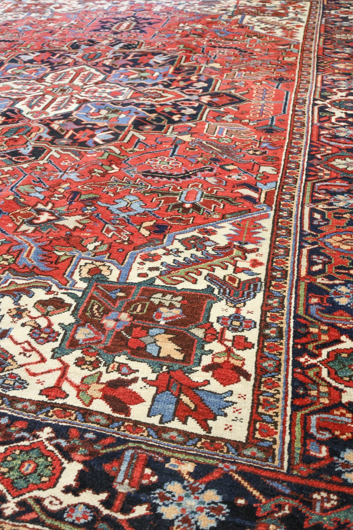 Handwoven Heriz rug detail, showcasing intricate red, blue, and ivory patterns.
