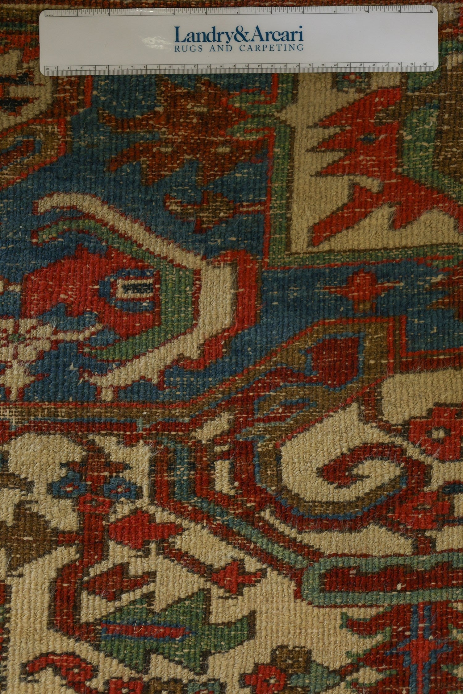 Close-up detail of a handwoven Heriz rug, showcasing its intricate red, blue, and beige pattern.
