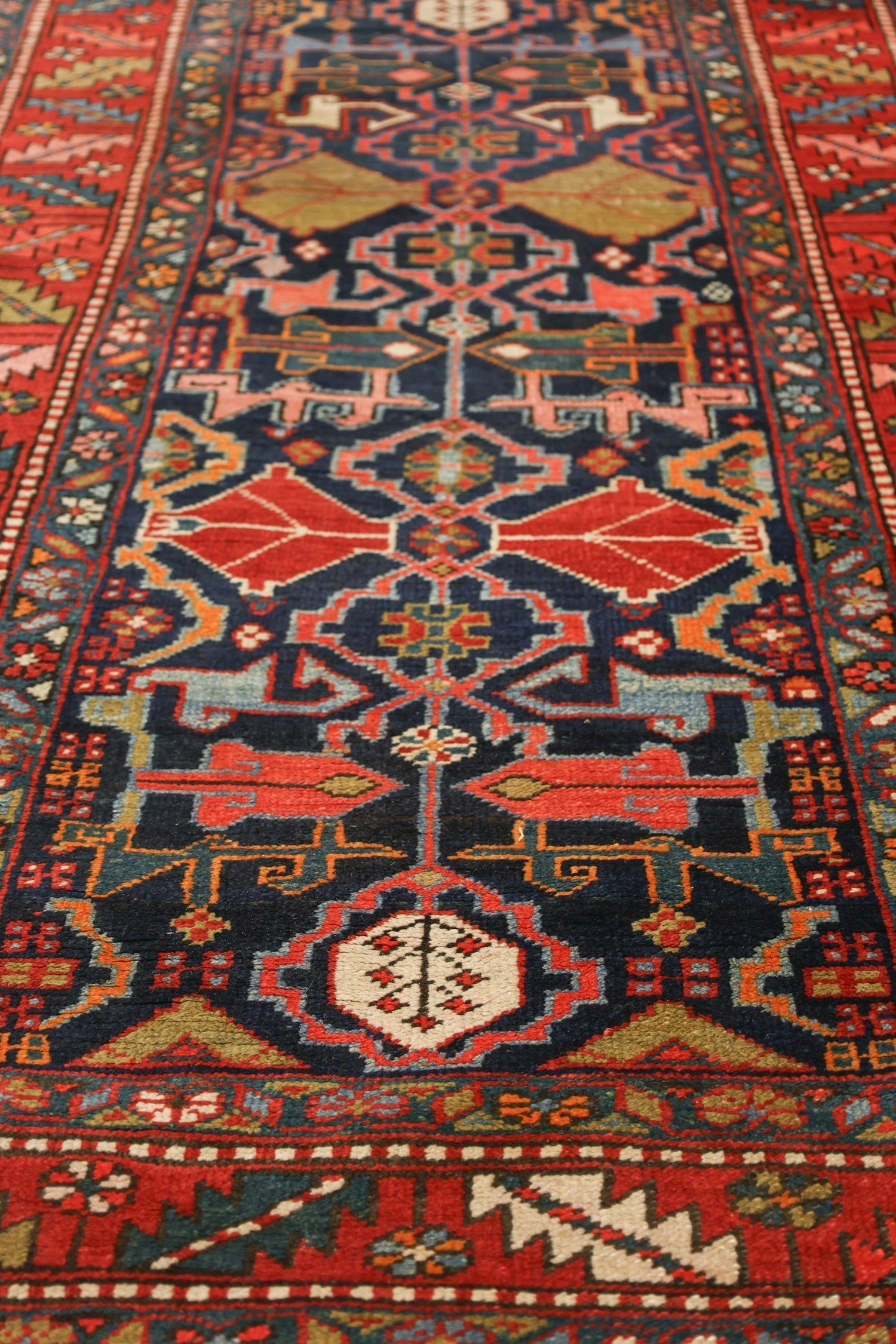 Handwoven Heriz rug detail, showcasing vibrant reds, blues, and intricate tribal patterns.
