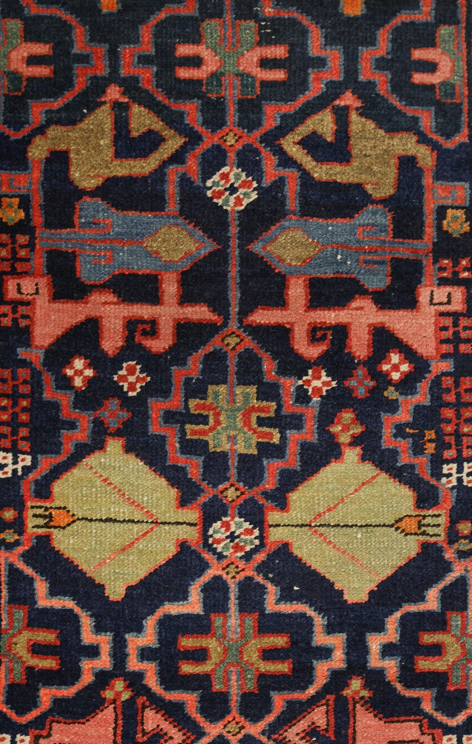 Close-up detail of a handwoven rug's intricate, multicolored geometric pattern.
