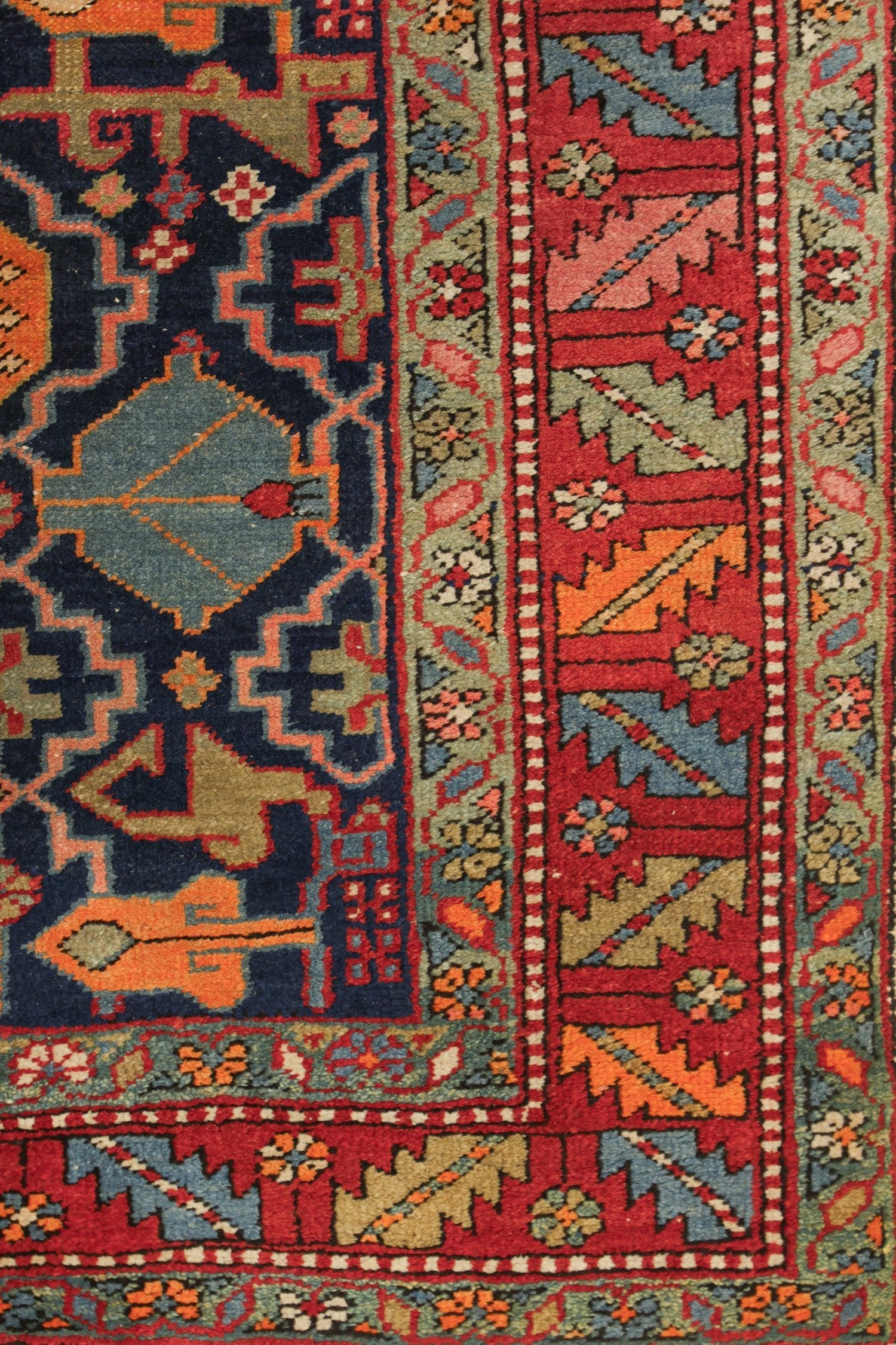 Handwoven Heriz rug detail, showcasing vibrant red, blue, and orange tribal patterns.
