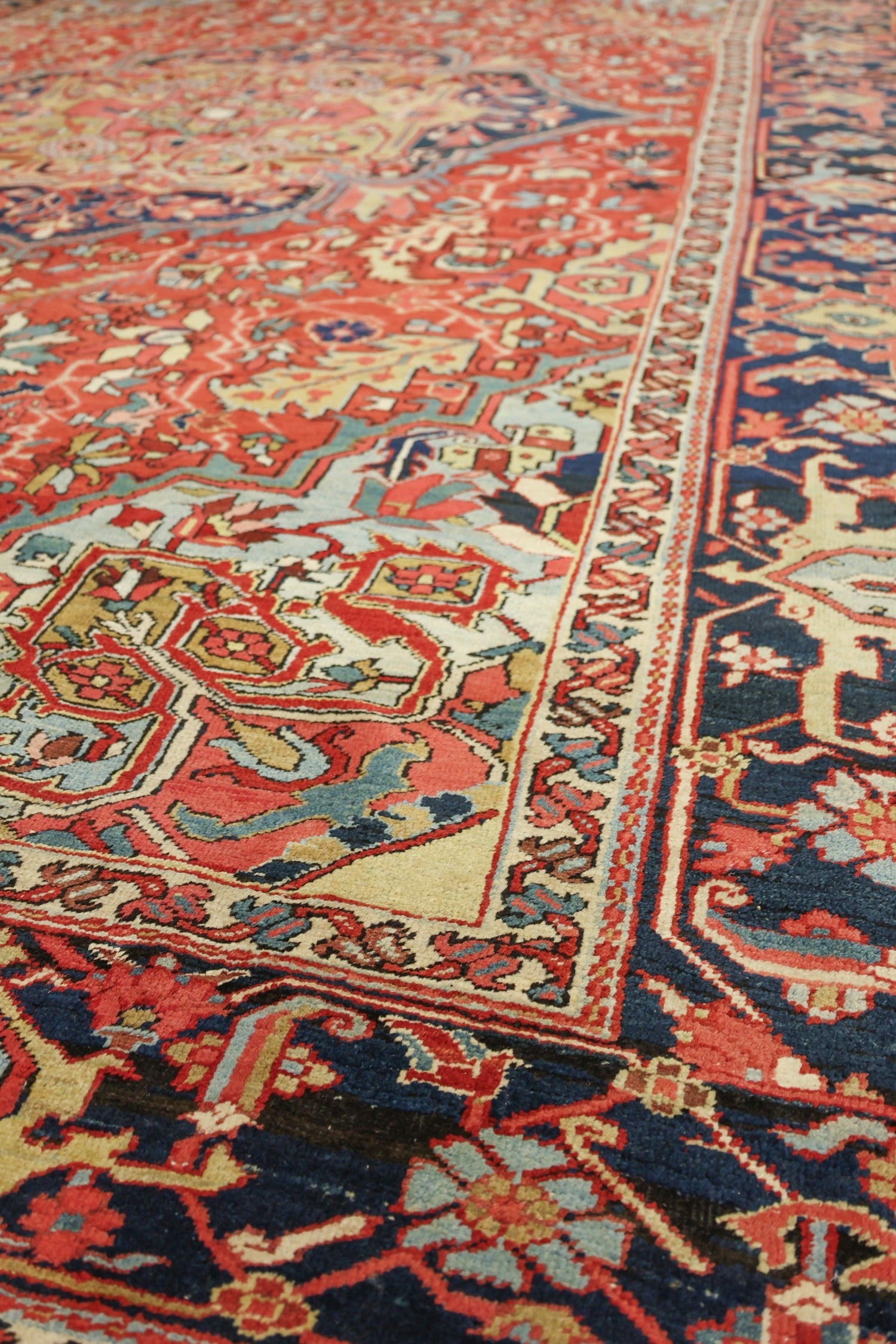 Handwoven Heriz rug detail, showcasing intricate red, blue, and beige patterns.
