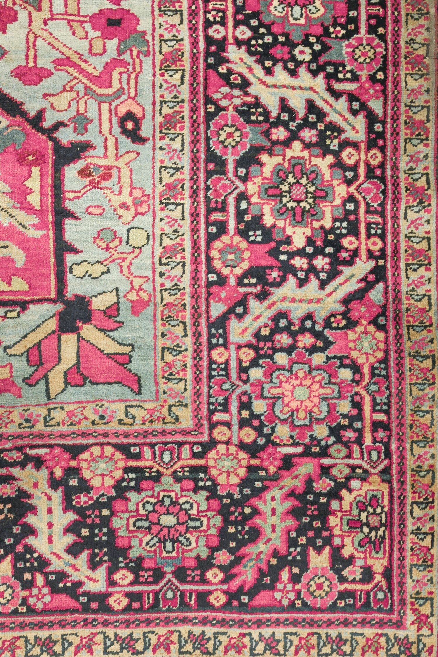 Handwoven Heriz rug detail, showcasing pink, black, and beige floral patterns.
