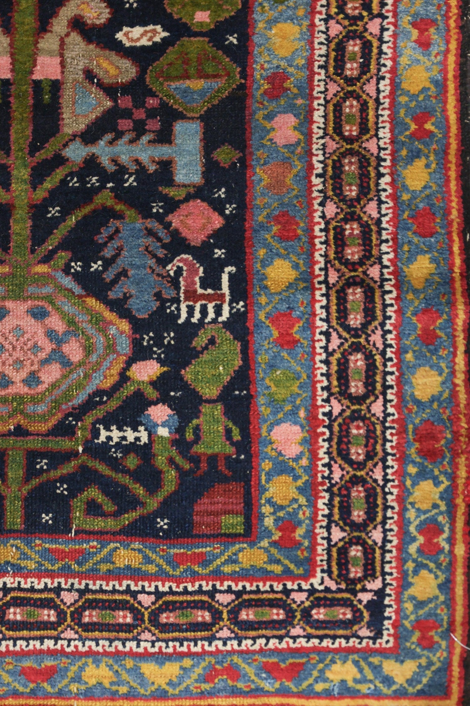 Handwoven Malayer rug detail, showcasing vibrant colors and intricate tribal patterns on a dark background.
