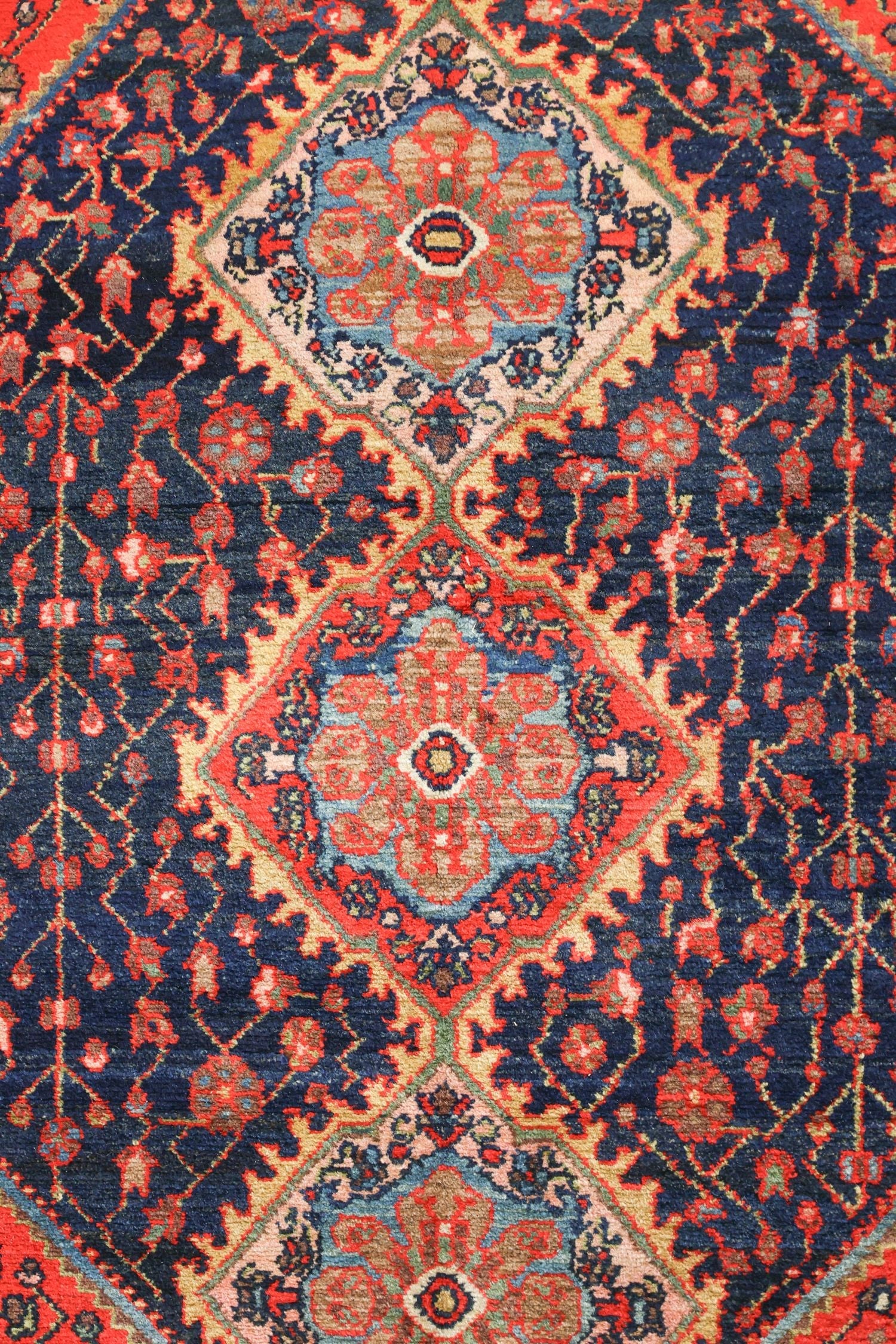 Intricate detail of a handwoven rug with red, blue, and beige floral patterns.
