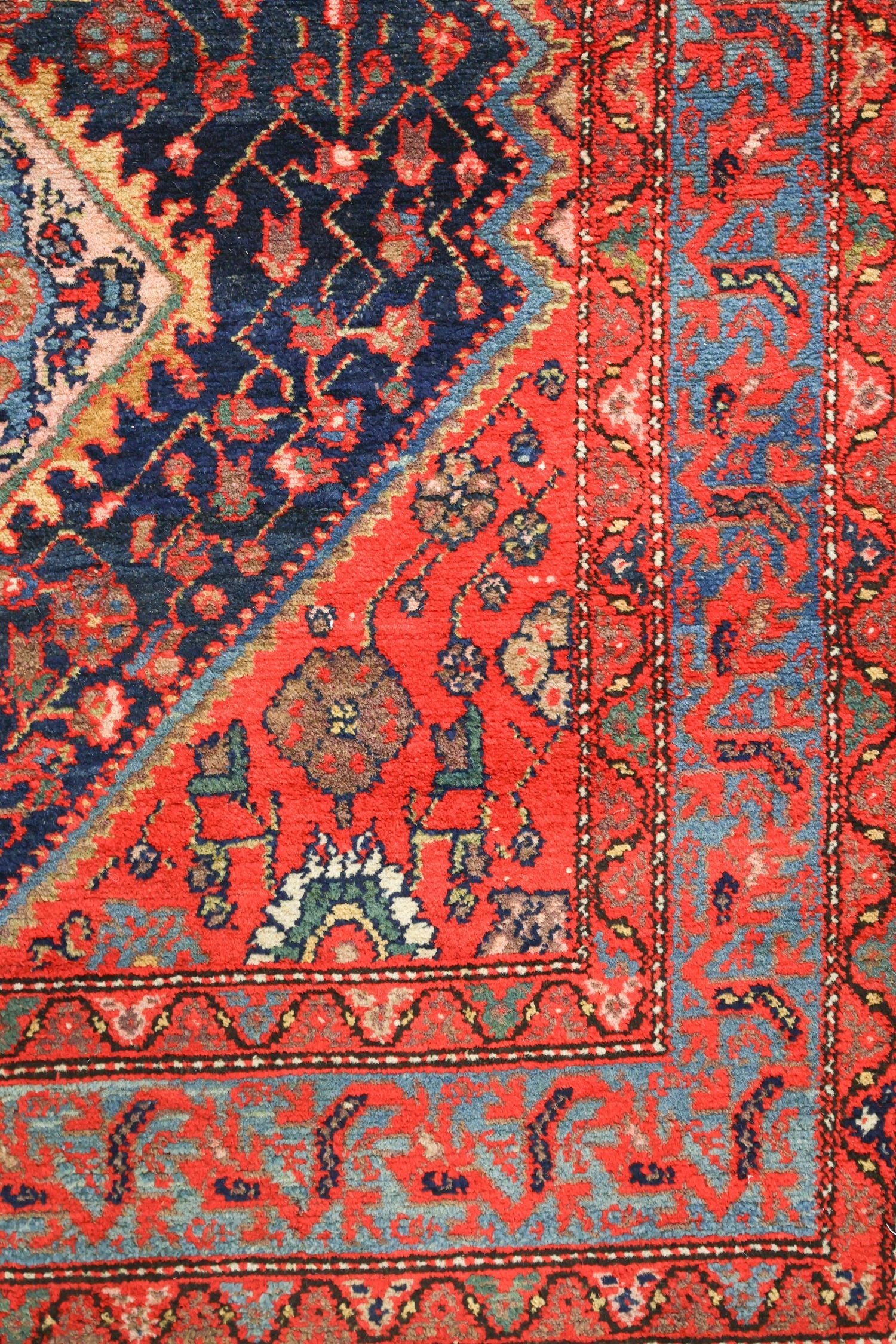 Detail of antique Malayer rug's handwoven, red and blue tribal pattern.
