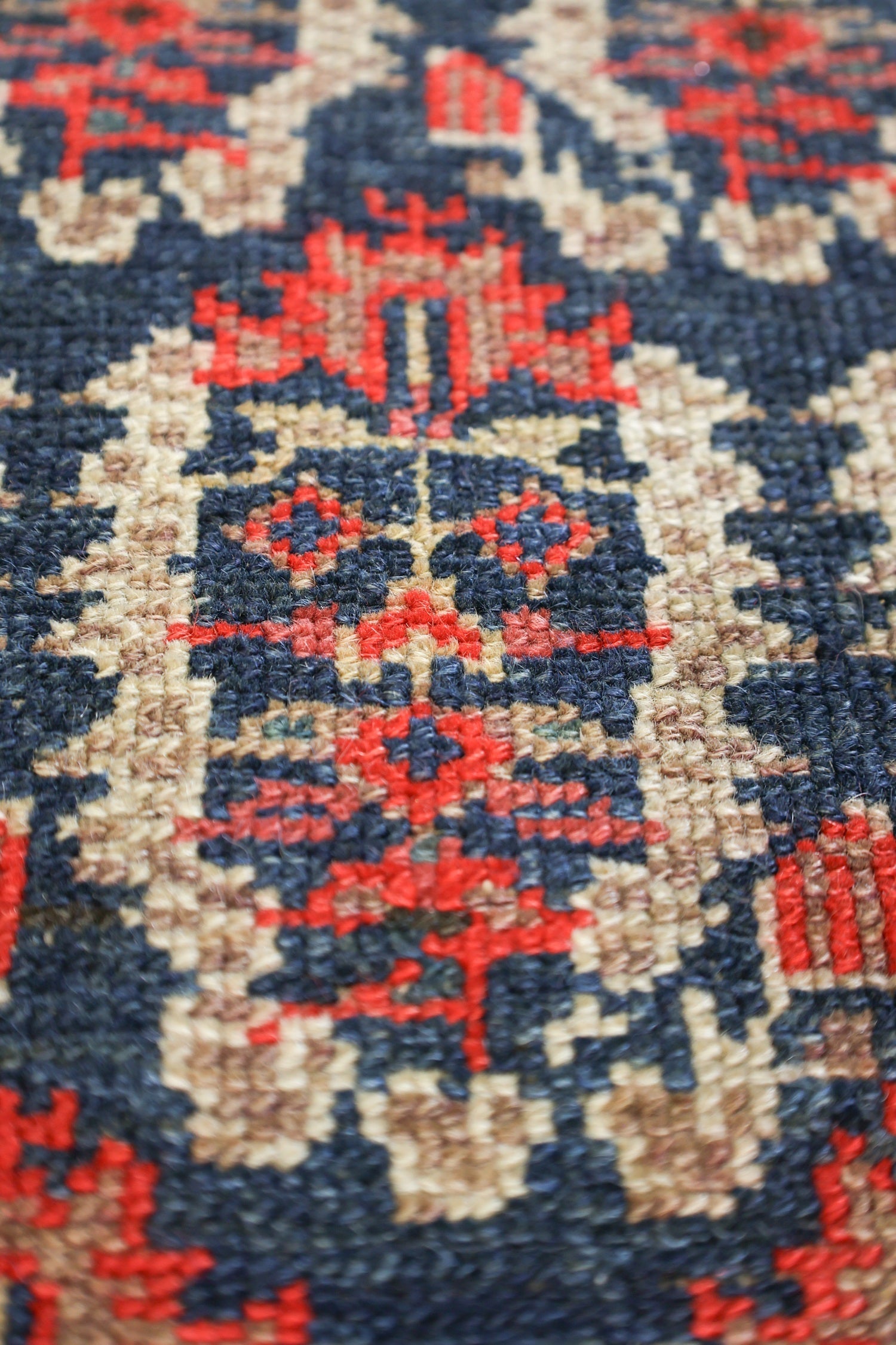 Close-up of antique Malayer rug's intricate, handwoven detail in navy, red, and beige.
