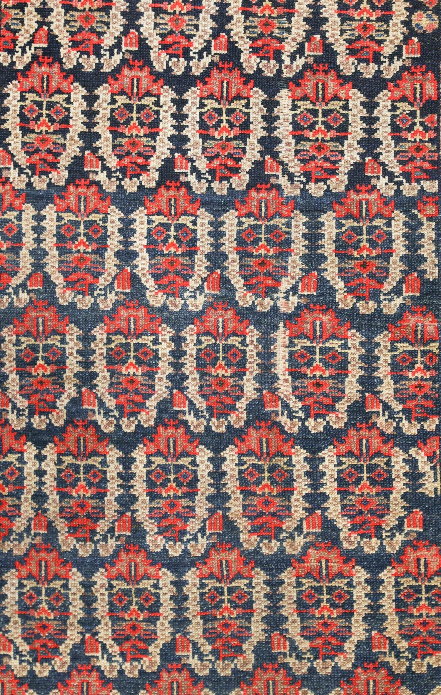 Handwoven tribal rug detail: intricate red, beige, and navy pattern.
