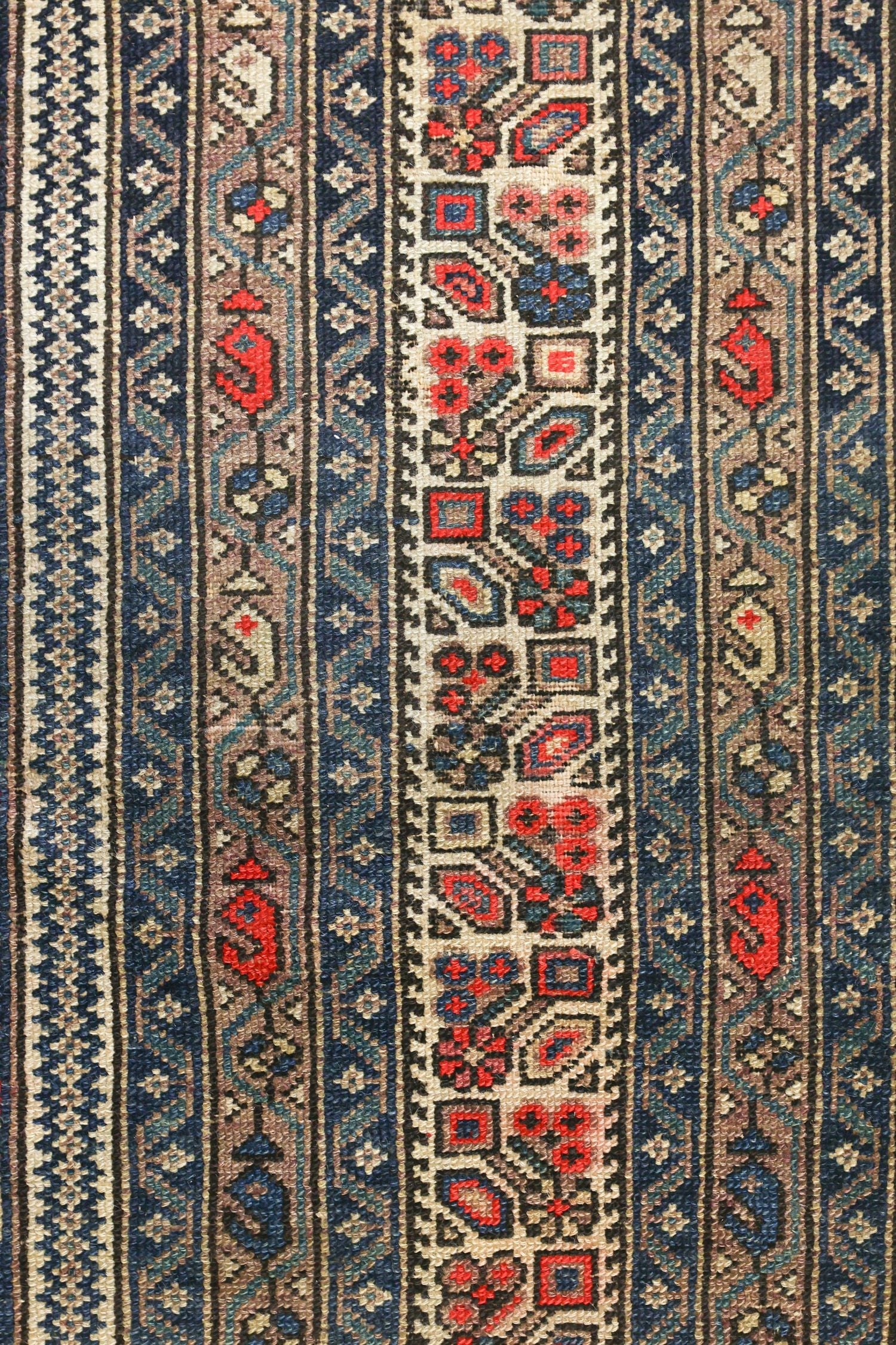 Close-up of antique Malayer rug's intricate, handwoven pattern in muted blues, reds, and beige.
