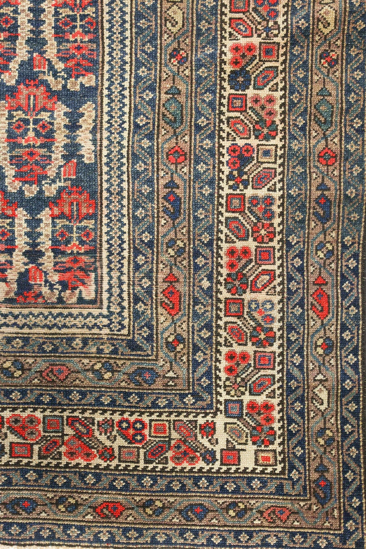 Detailed close-up of an antique Malayer rug's intricate handwoven border, showcasing a vibrant array of floral and geometric patterns in red, blue, and beige.
