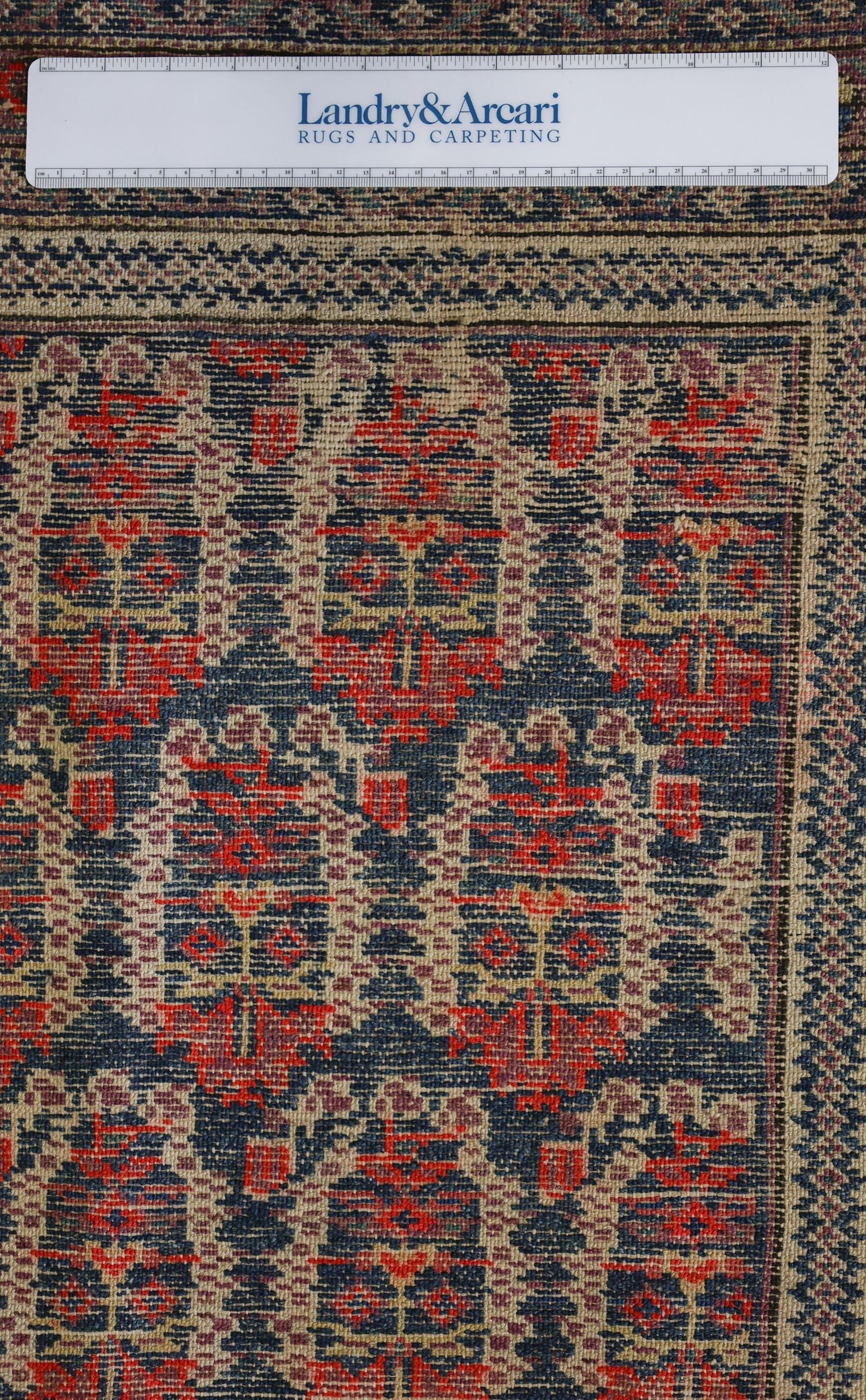 Close-up detail of antique Malayer rug's handwoven, red and blue floral pattern.
