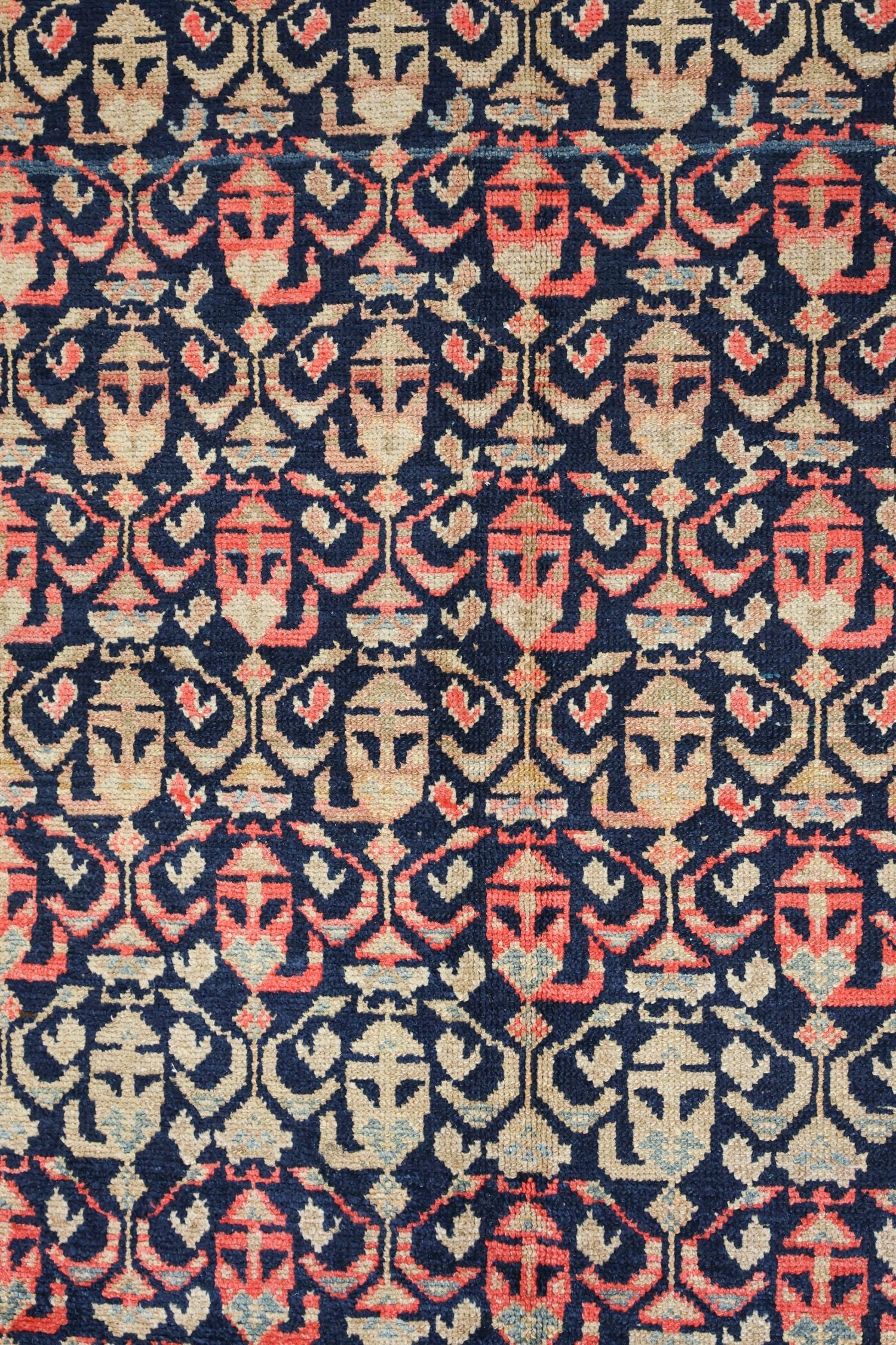 Handwoven tribal rug detail: intricate navy blue pattern with coral and beige accents.
