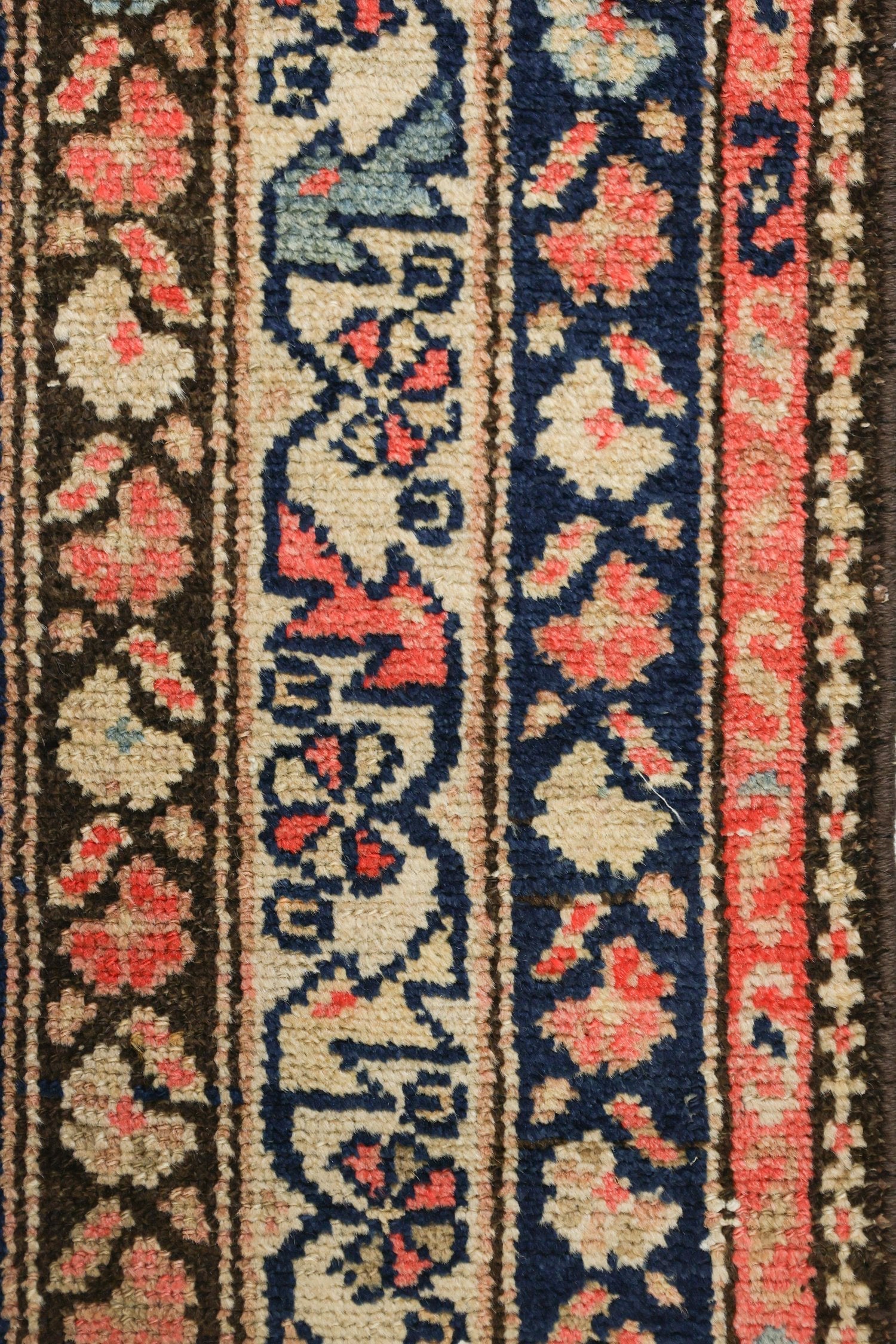 Close-up of antique Malayer rug's intricate, handwoven floral pattern in muted reds, blues, and beige.
