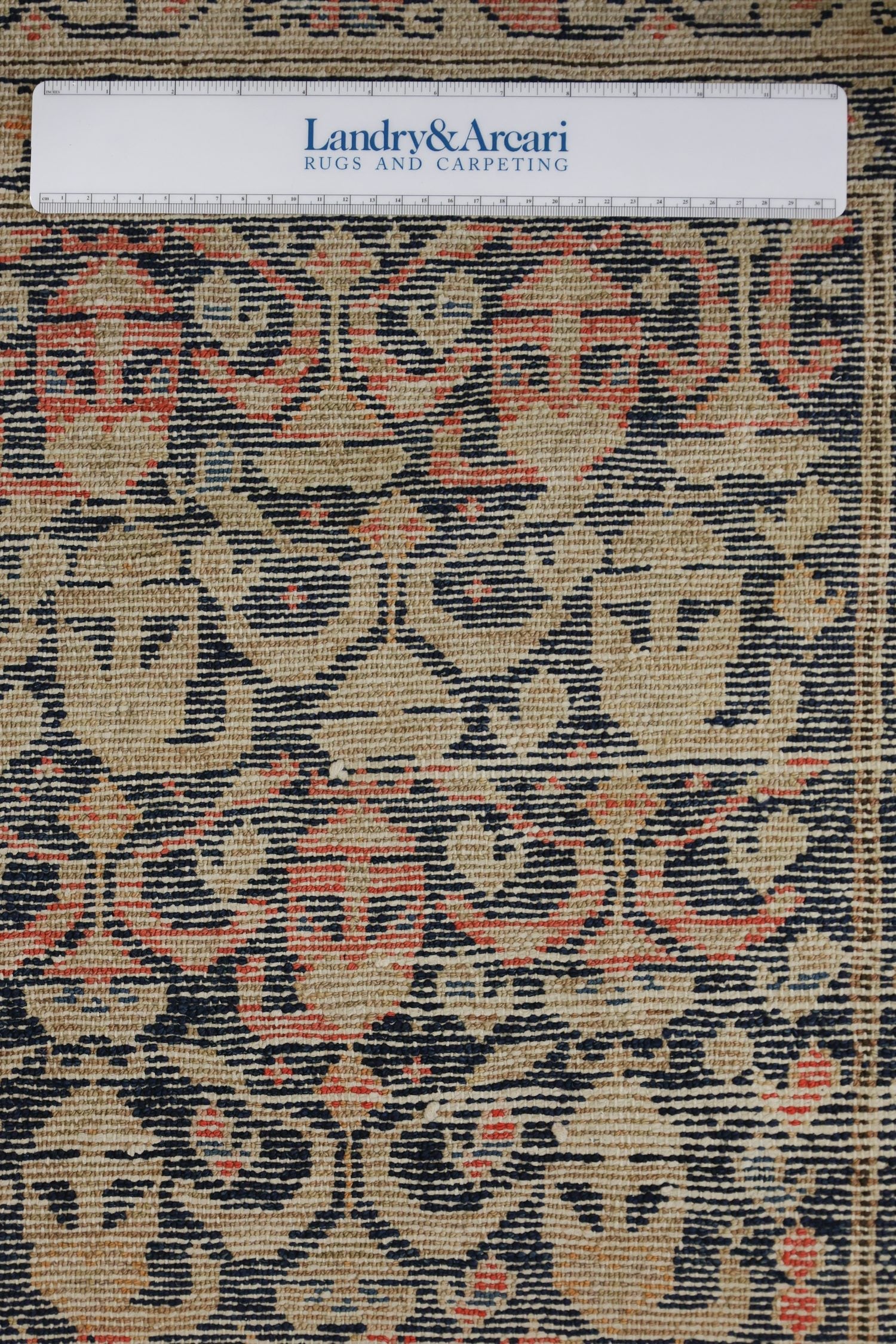 Close-up detail of antique Malayer rug's handwoven, intricate pattern in beige, navy, and coral.
