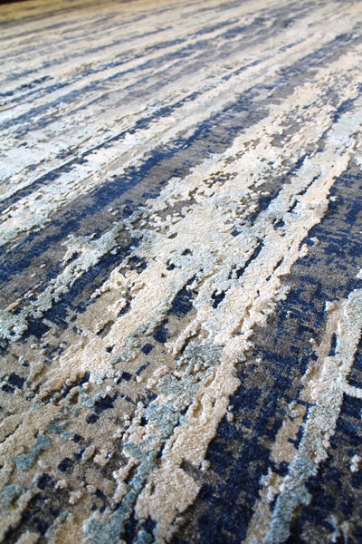 Close-up of handwoven rug's textured, abstract design in blues and creams.
