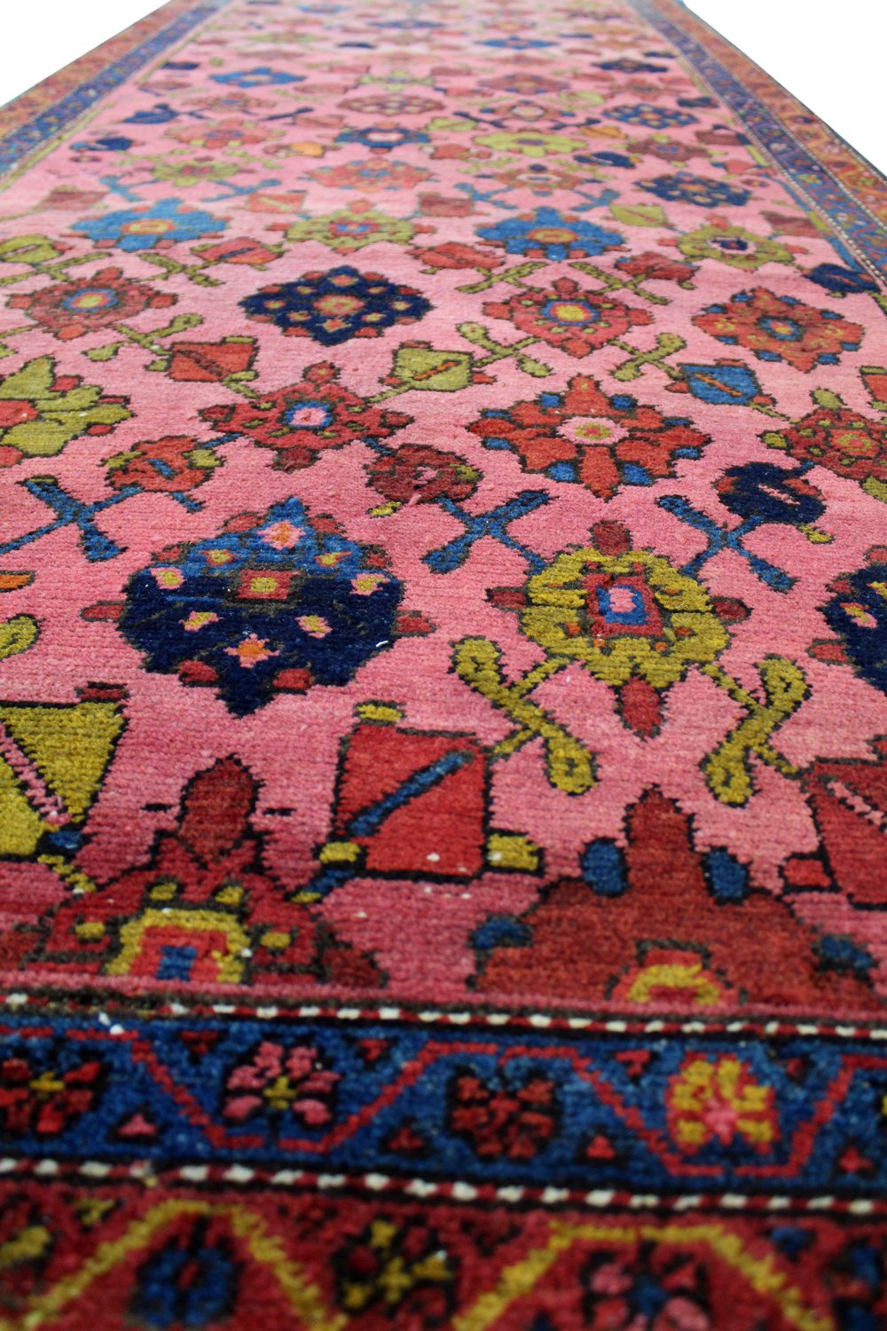 Close-up of a pink antique Hamadan rug, showcasing intricate floral details and vibrant colors.
