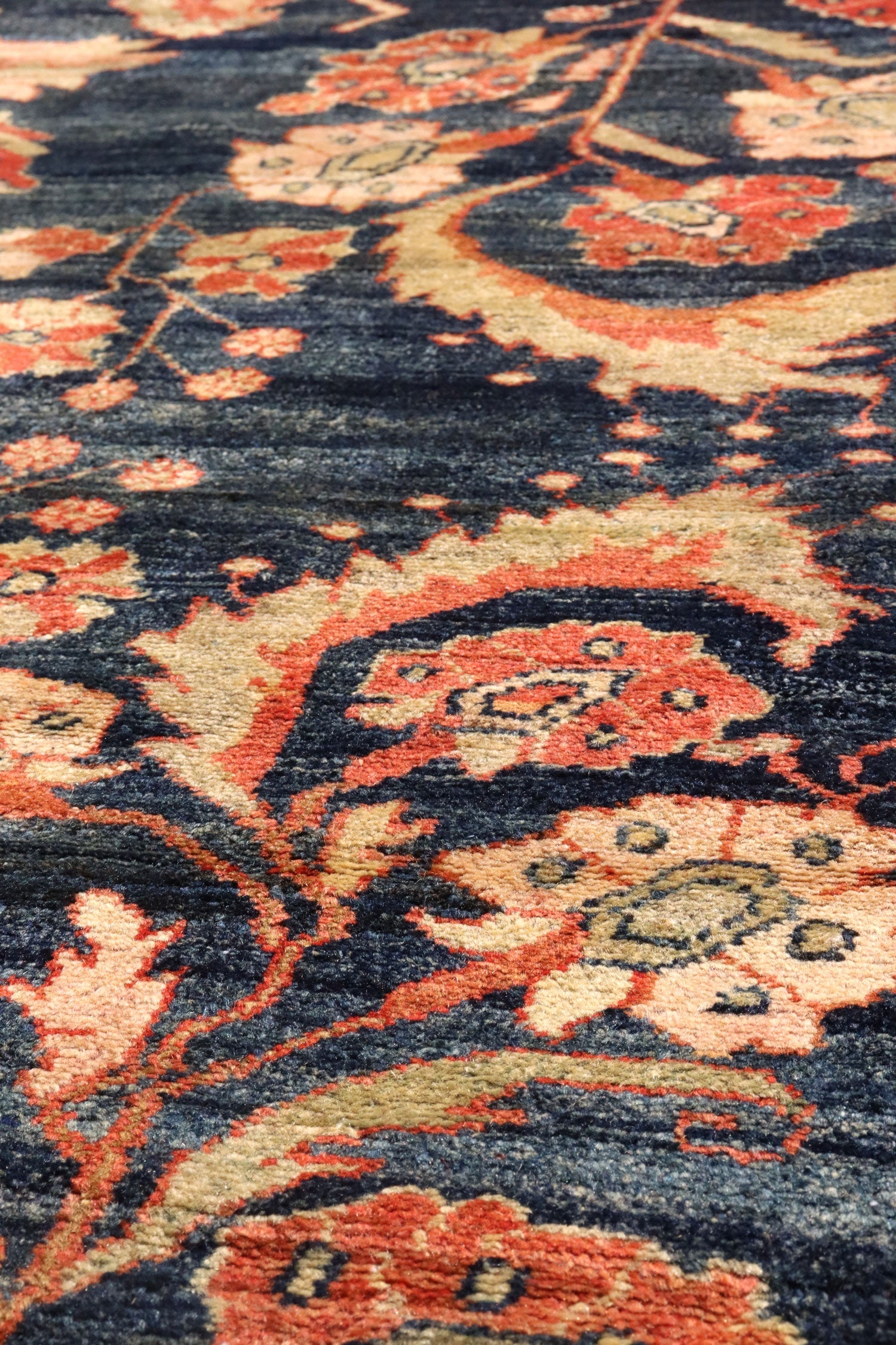 Close-up of a richly colored antique rug with intricate floral details in shades of red, beige, and navy.
