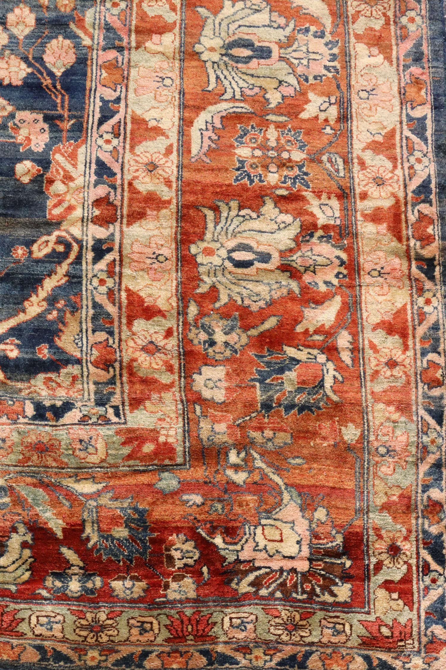 Detail of antique handwoven rug; red, blue, and beige floral patterns.
