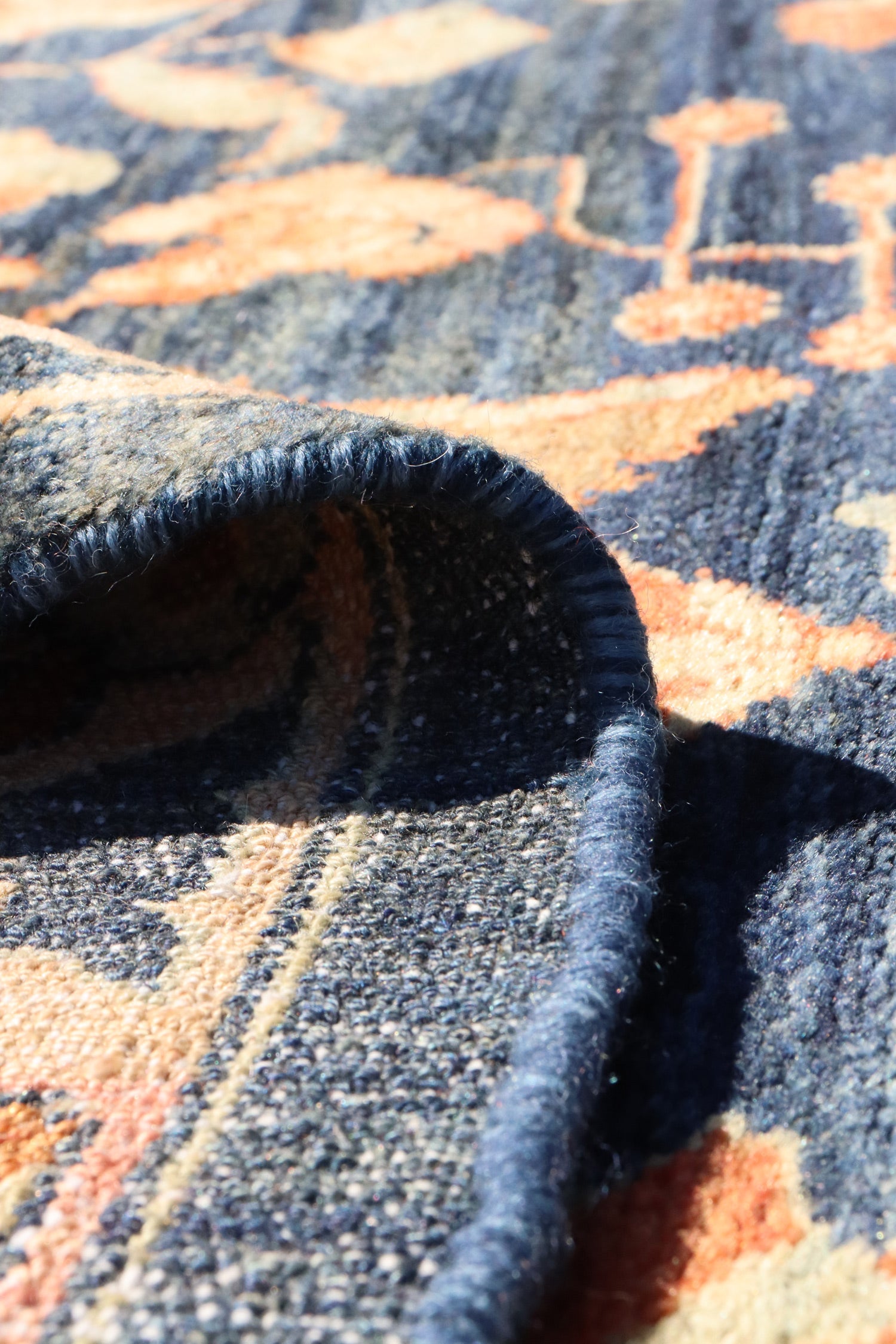 Handwoven rug detail: close-up of deep blue and orange pattern, showcasing the texture and craftsmanship.
