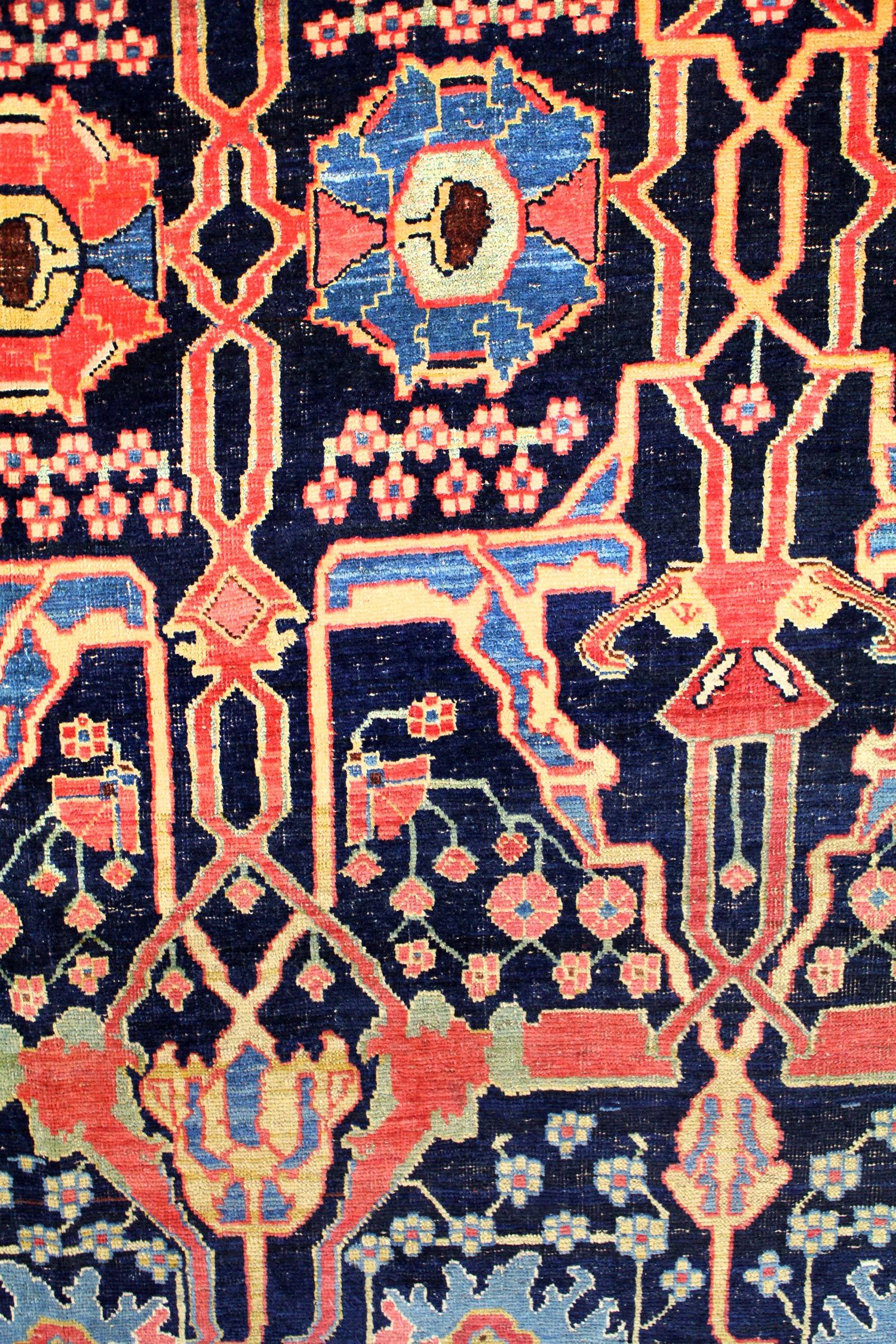 Intricate detail of a traditional Bijar rug, showcasing a navy blue background with red and blue floral patterns.
