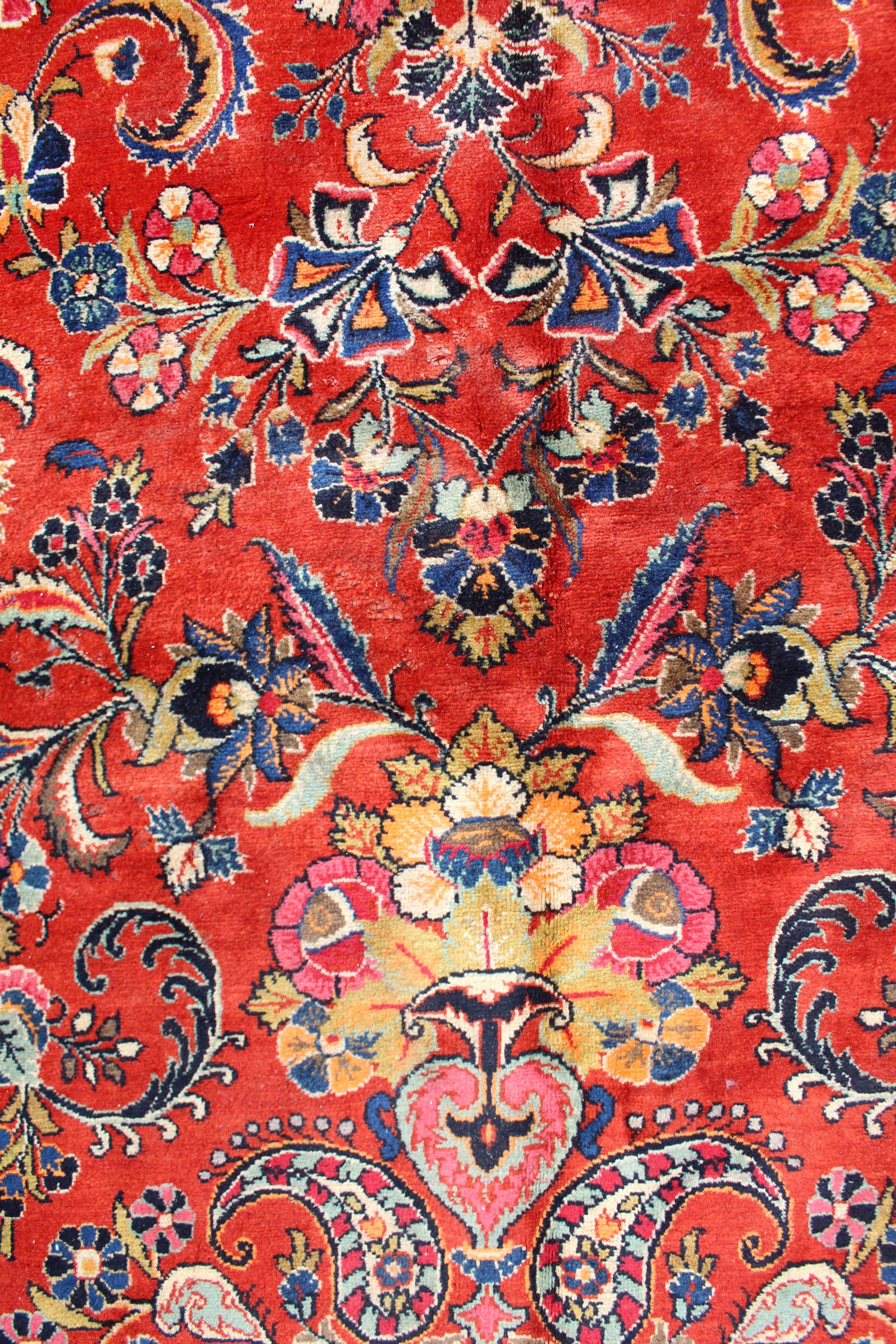 Intricate red handwoven rug detail, showcasing a floral and paisley design in various colors.
