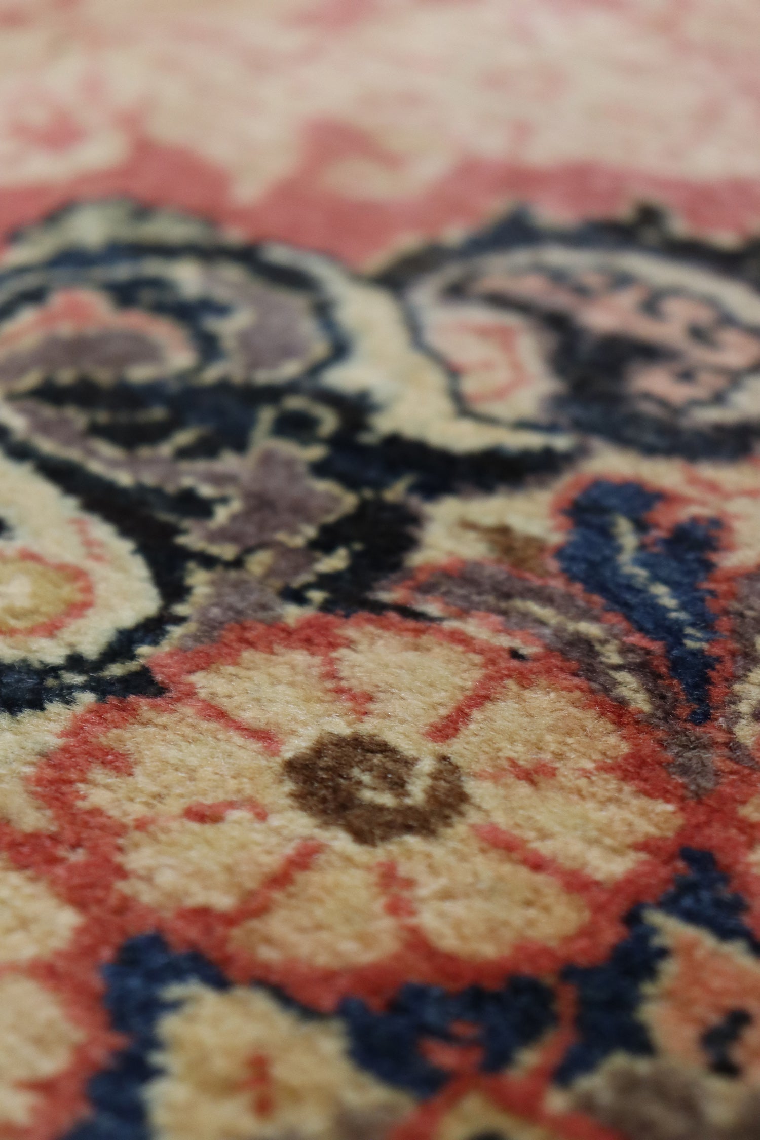 Close-up detail of a handwoven rug’s floral pattern in muted reds, creams, and blues.
