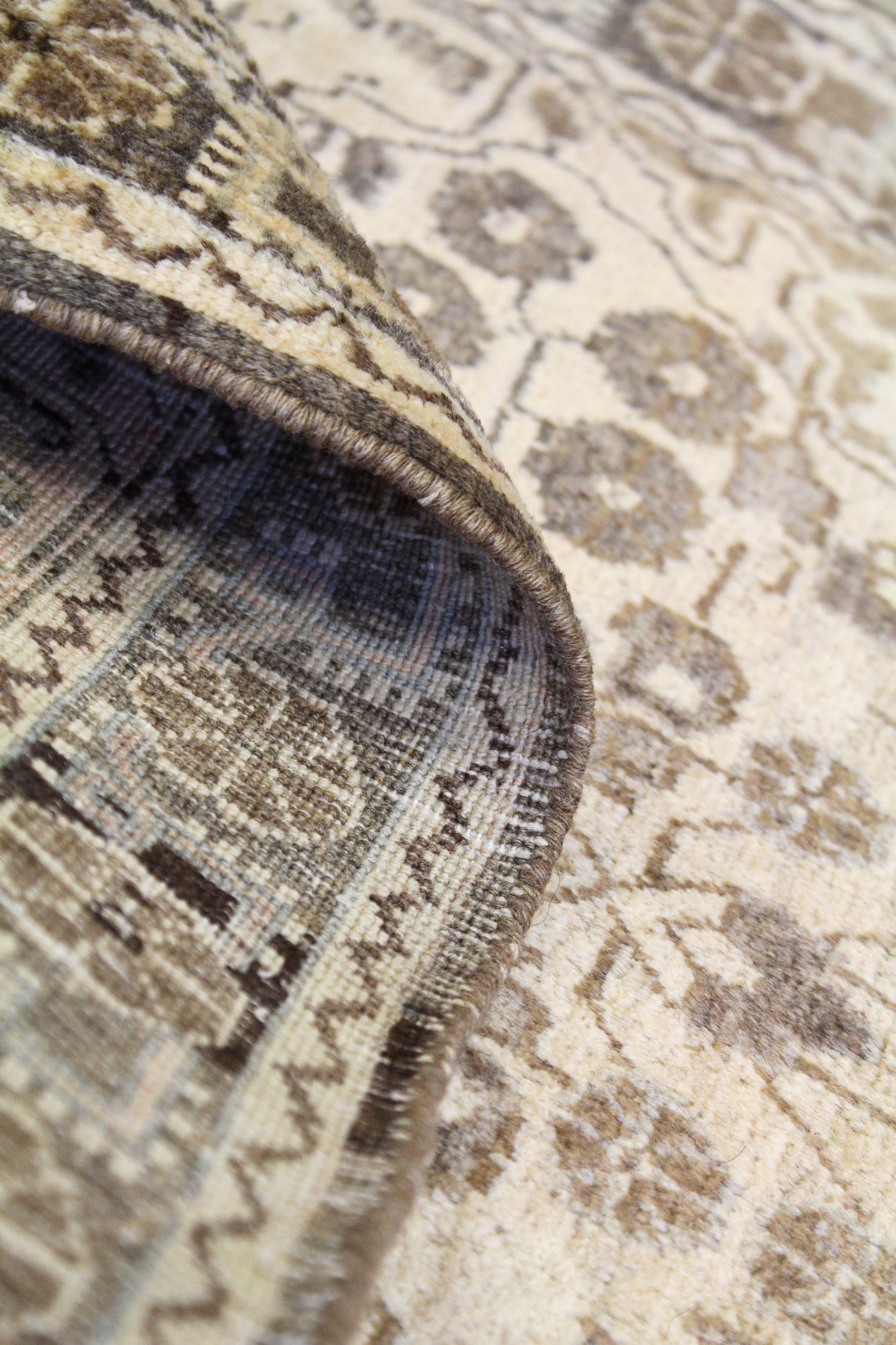 Close-up of antique rug's handwoven texture, showcasing neutral tones and intricate detailing.
