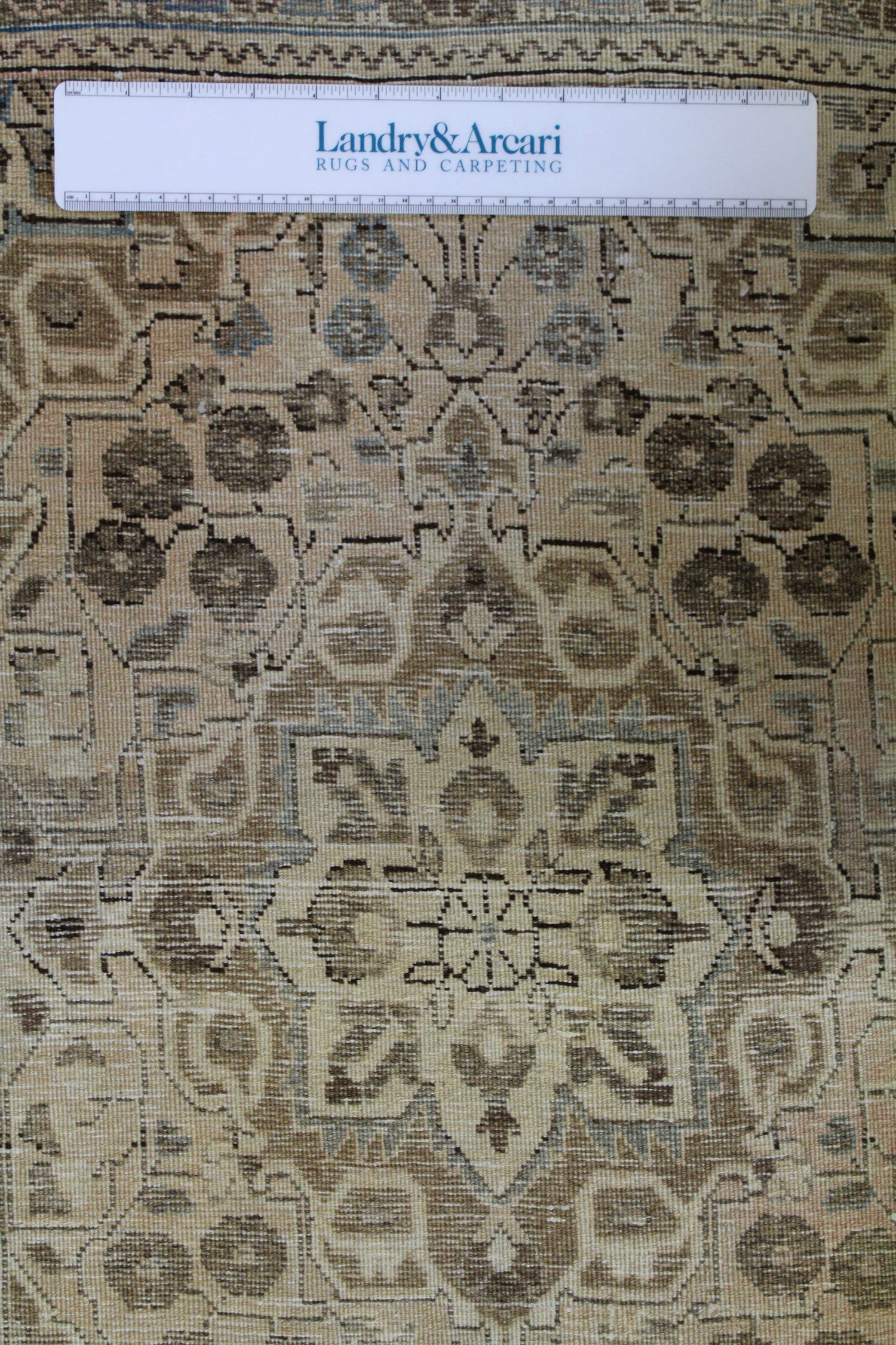 Detailed close-up of antique Sarouk rug's muted beige and brown handwoven pattern.
