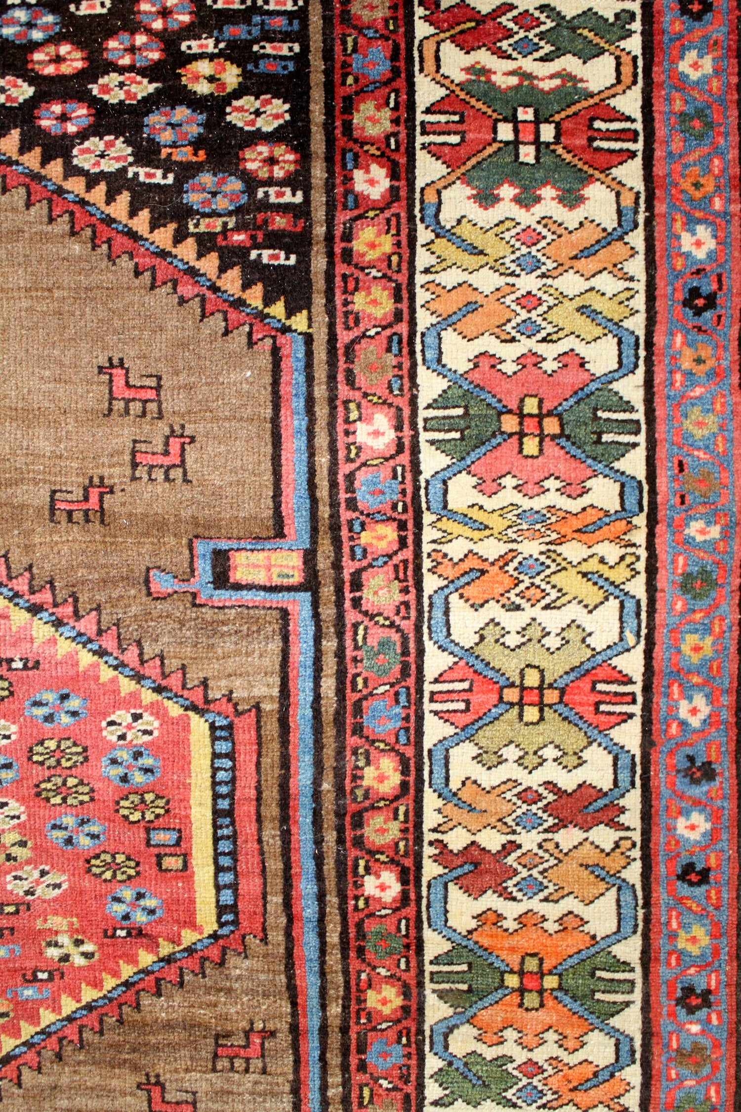 Detail of antique Bijar rug showcasing vibrant, handwoven tribal patterns in red, blue, and beige.
