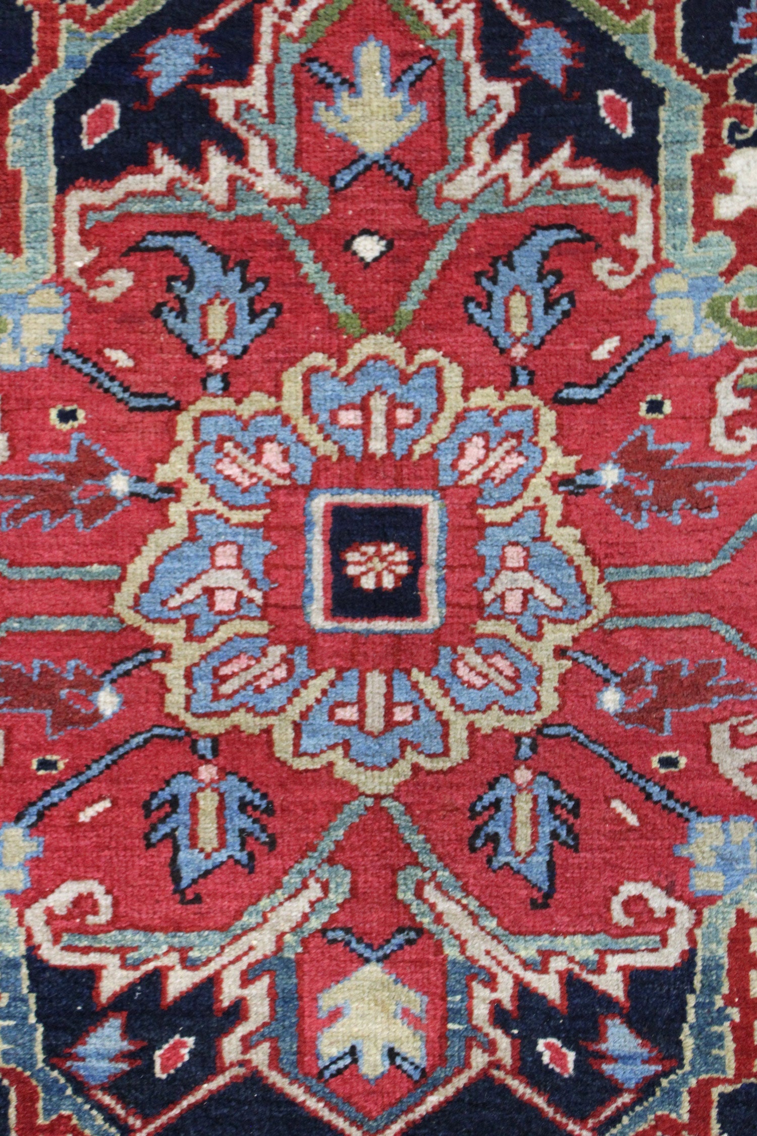 Close-up of a red and blue antique Heriz rug, showcasing intricate handwoven tribal patterns.
