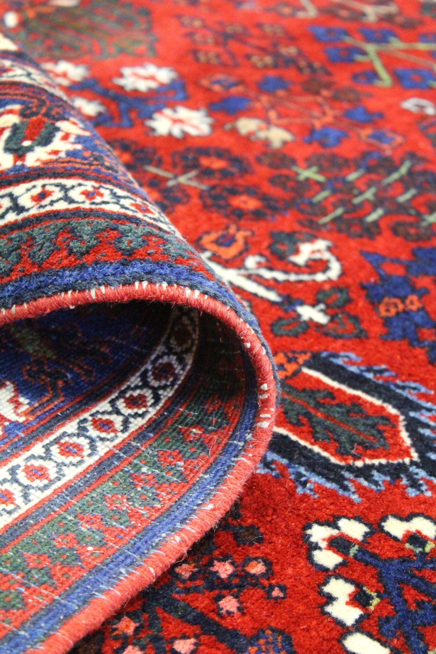 Close-up of handwoven rug detail, showcasing vibrant red, blue, and cream patterns in a traditional tribal design.
