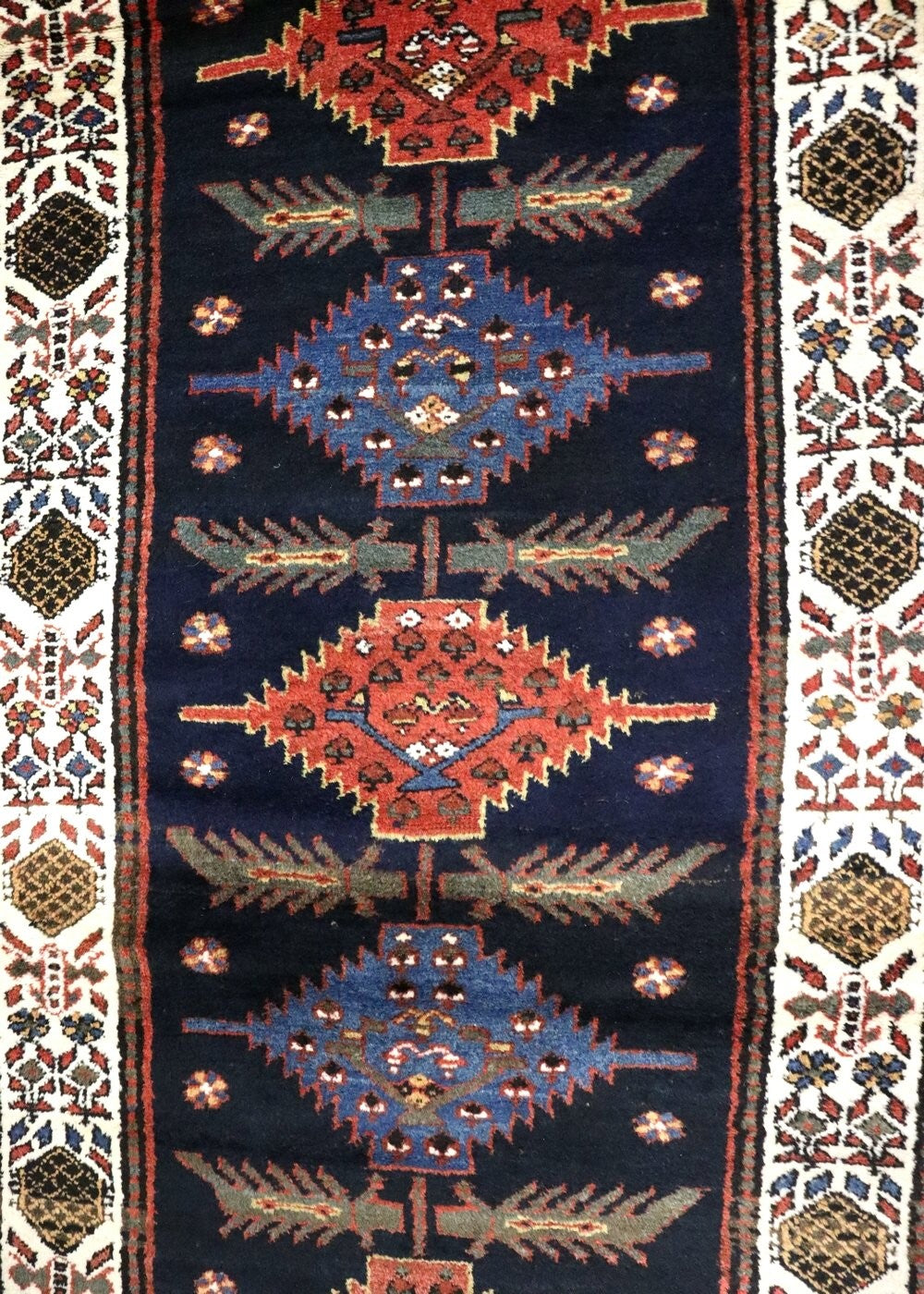 Handwoven tribal rug detail: intricate navy blue, red, and white geometric patterns.
