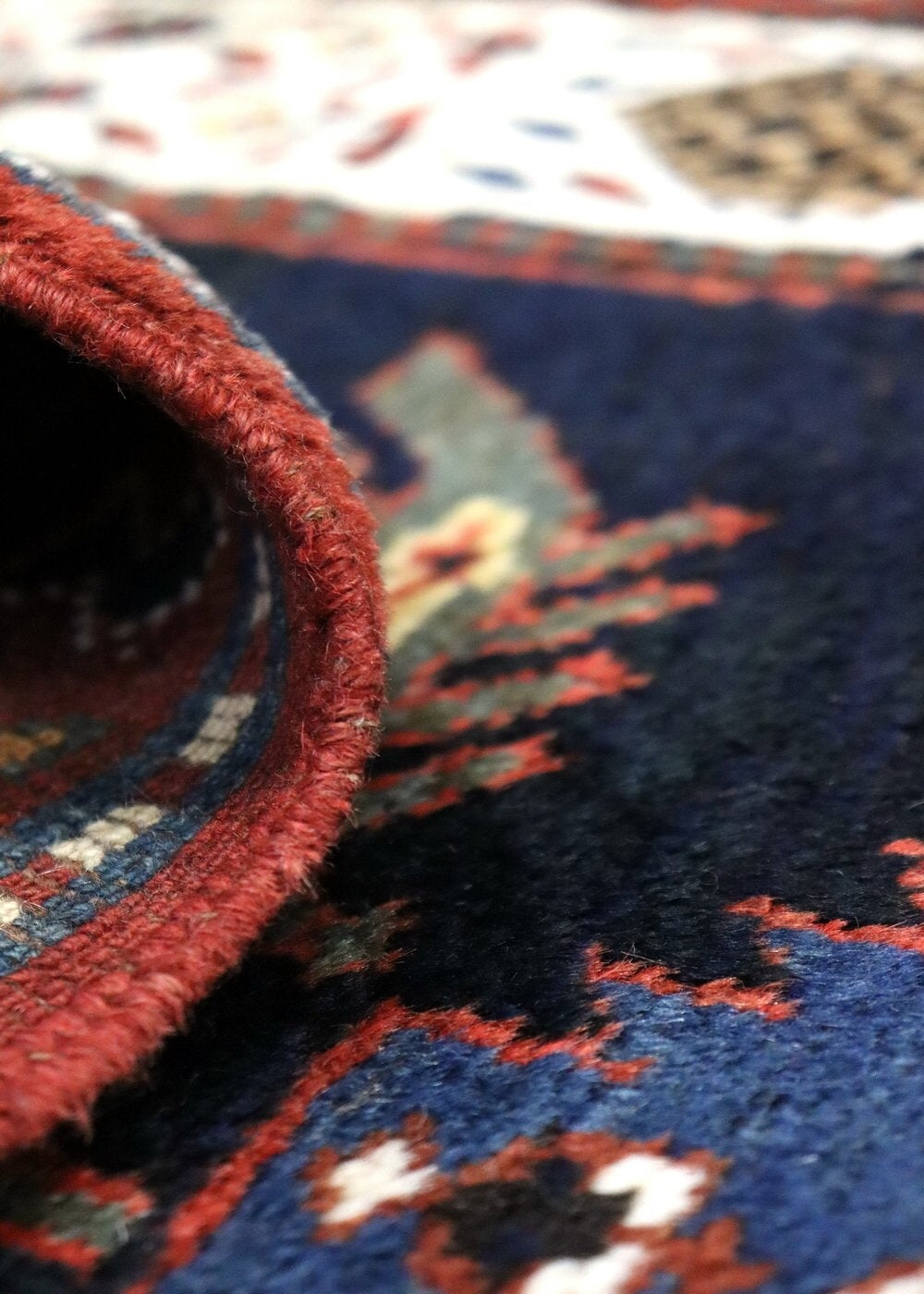 Handwoven rug detail: rich red fringe and navy blue, red & white pattern.
